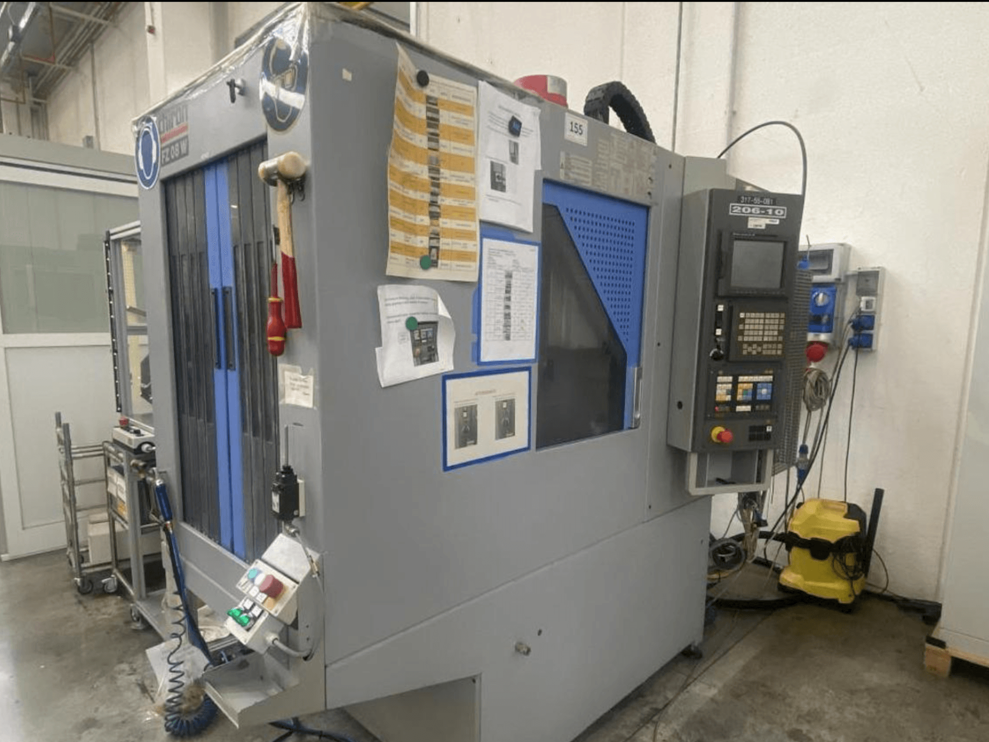 CNC stroj Shin Lin, pohled zepředu, s ovládacím panelem, ovládacími tlačítky a přiloženými bezpečnostními pokyny.