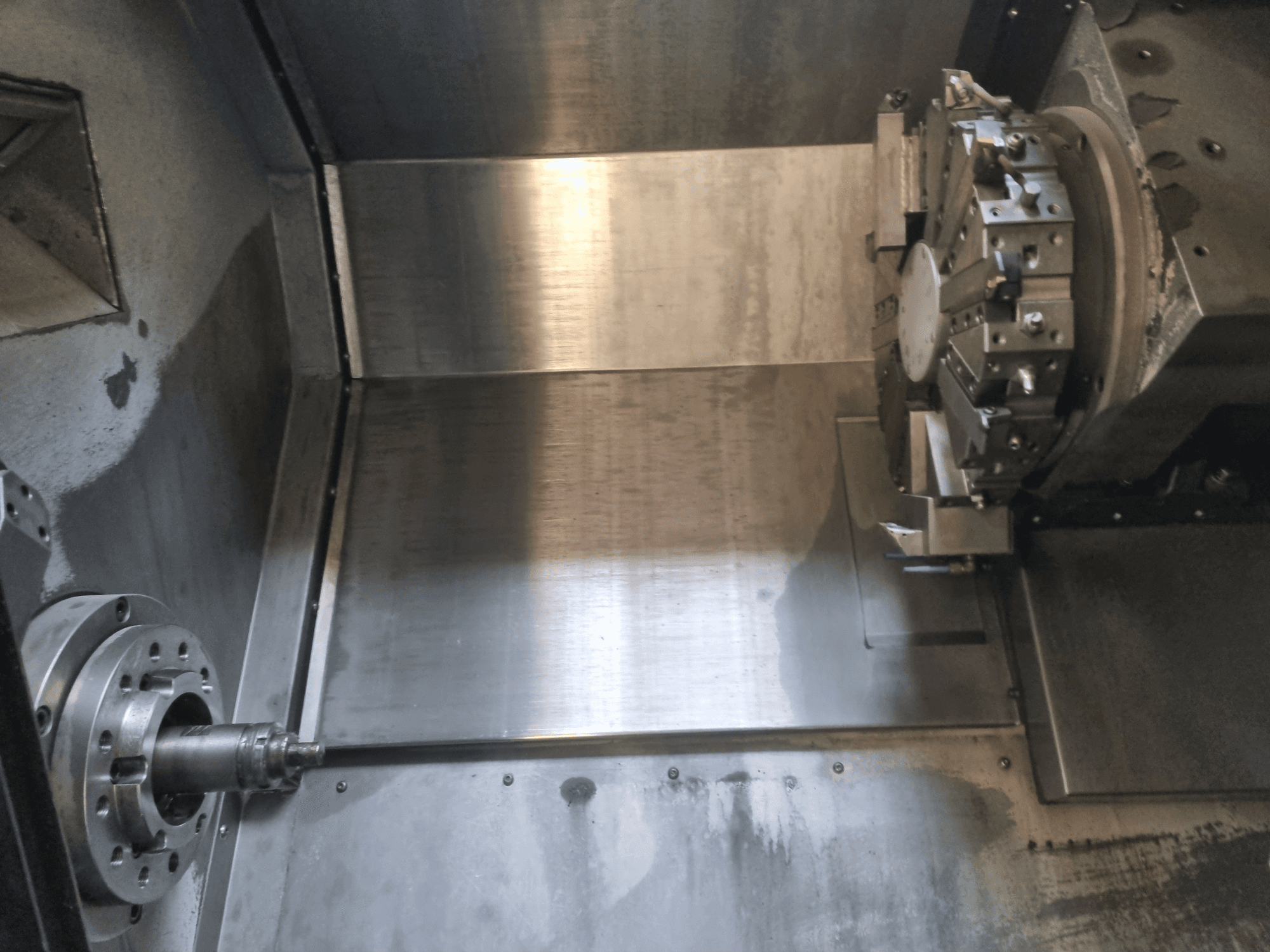 Pohled do interiéru CNC soustruhu s rotujícím vřetenem a kovovou pracovní plochou, který je ukázkou přesného průmyslového strojírenství.