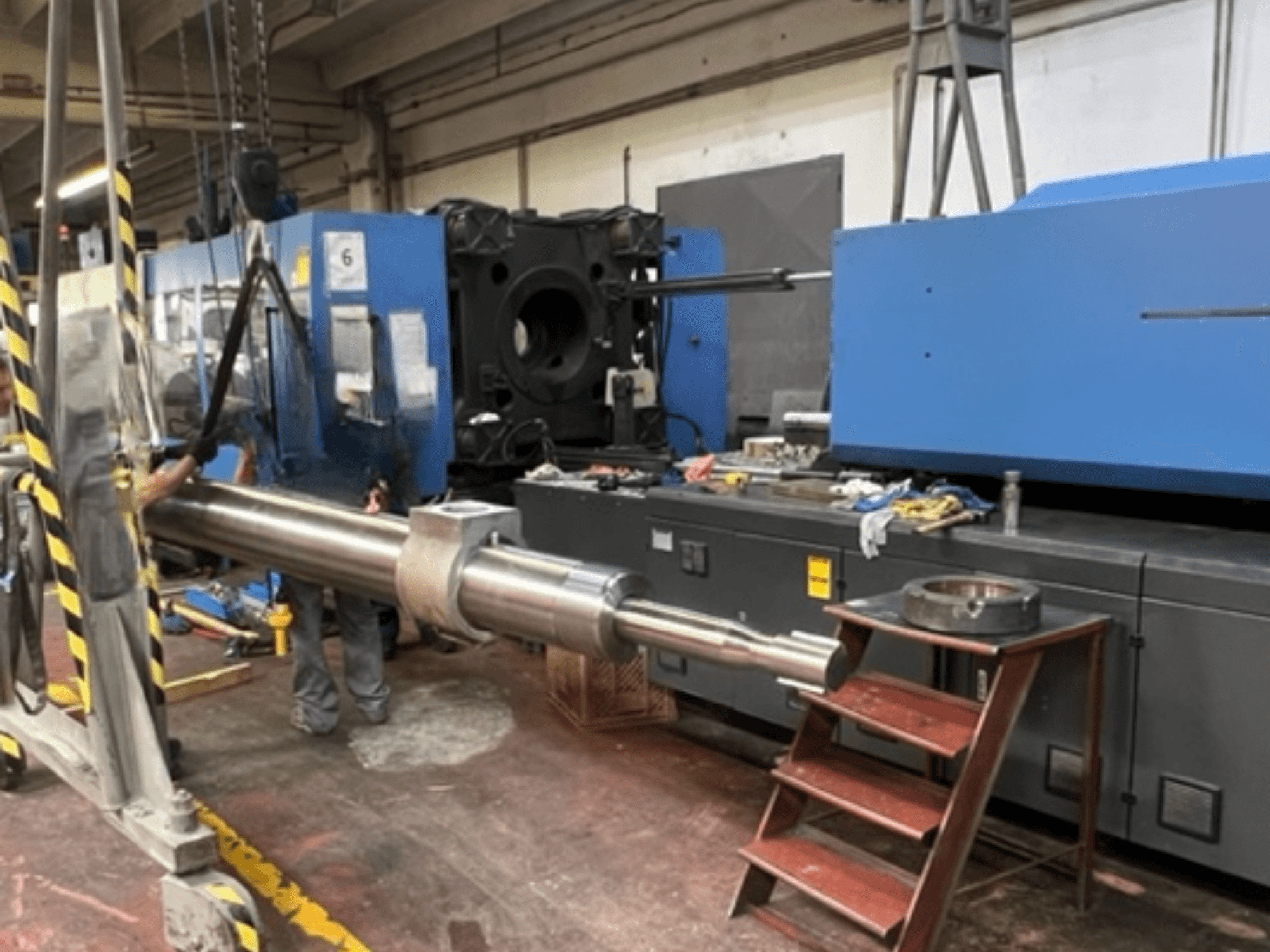 Hydraulický vstřikovací lis HAITIAN SA8000, zobrazený z boku při zvedání velké hydraulické pístnice.