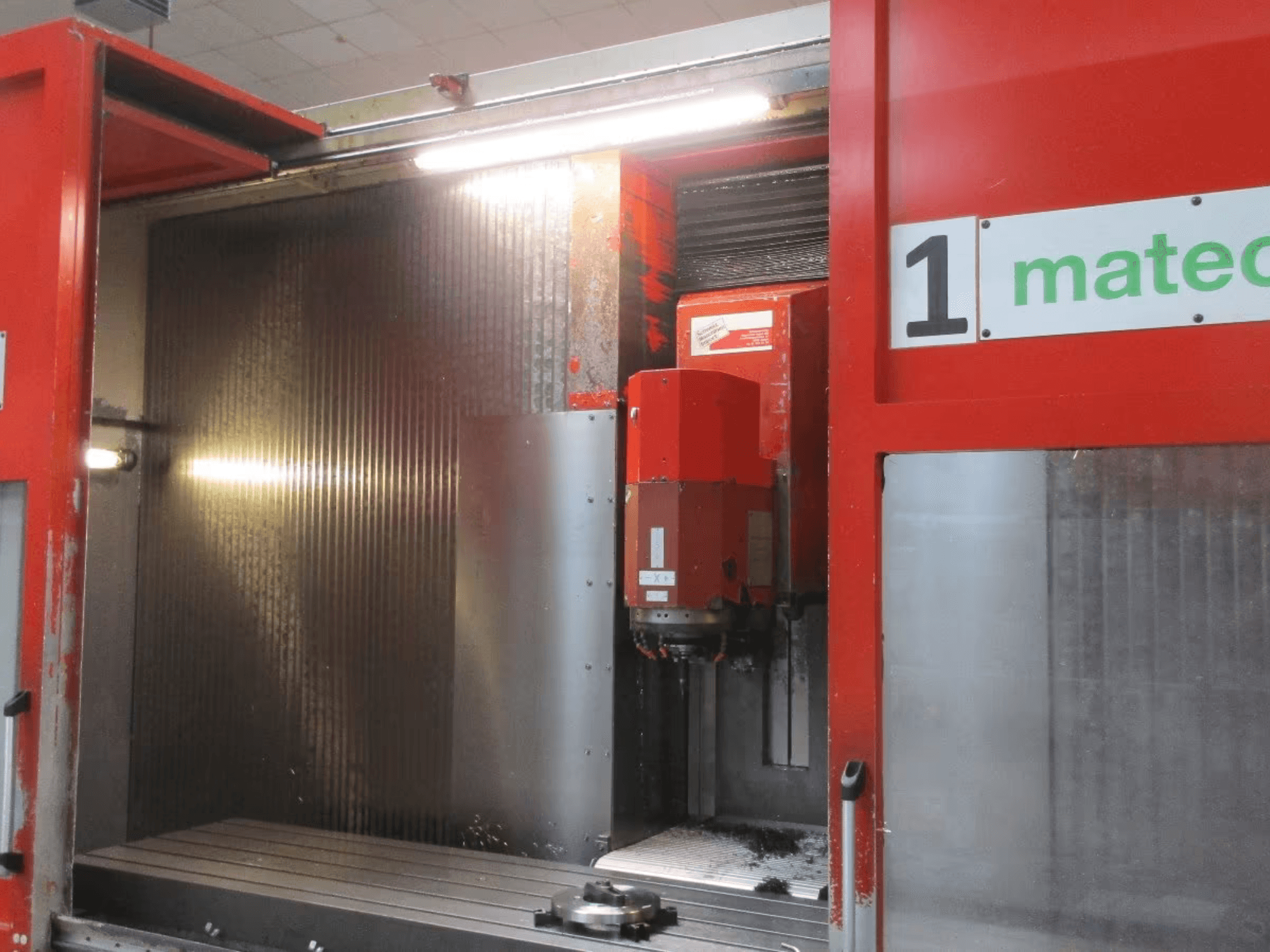 Pohled zepředu na CNC vertikální obráběcí centrum Matec 30 HV s viditelnými detaily řezného nástroje, kovového povrchu a vnitřku stroje.