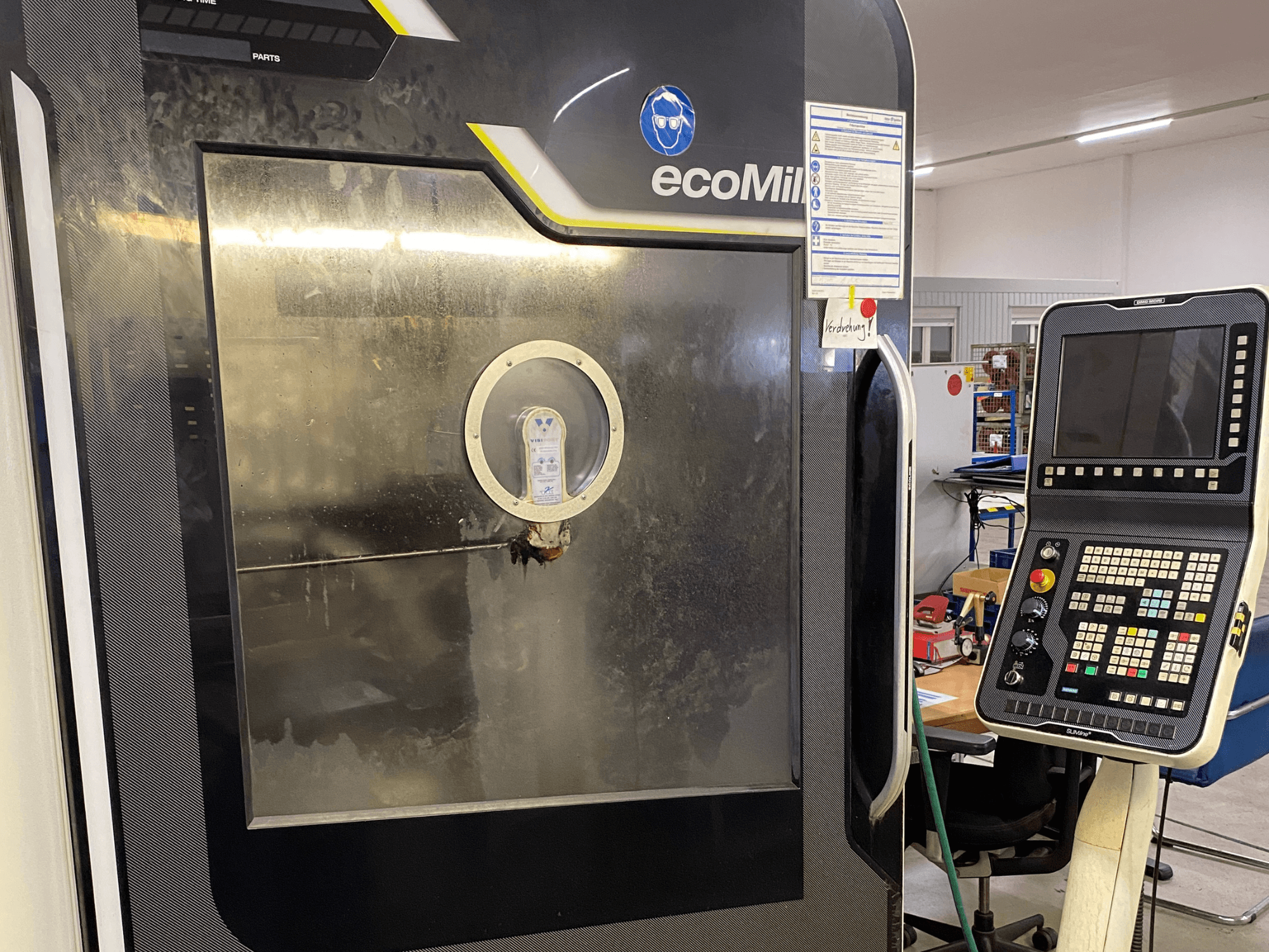 Frézka DMG MU 70 ECO v čelním pohledu, s ovládacím panelem vpravo a proskleným panelem, který odhaluje vnitřní součásti.