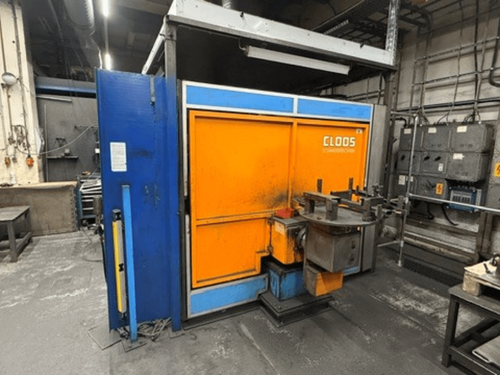 Svařovací robot CLOOS Romat 320 v dílně, pohled zepředu na oranžový a modrý kryt s ovládacím panelem a nástroji.