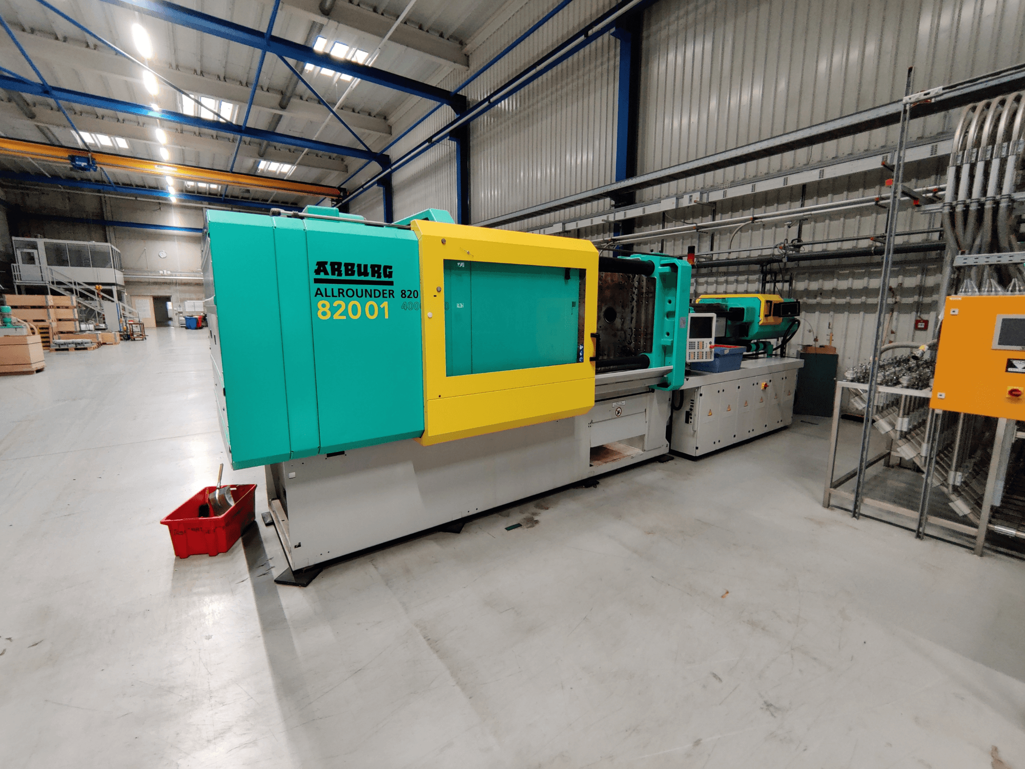 Pohled zepředu na hydraulický vstřikovací stroj Arburg 820 S 4000-2100 s jasně zelenými a žlutými panely.