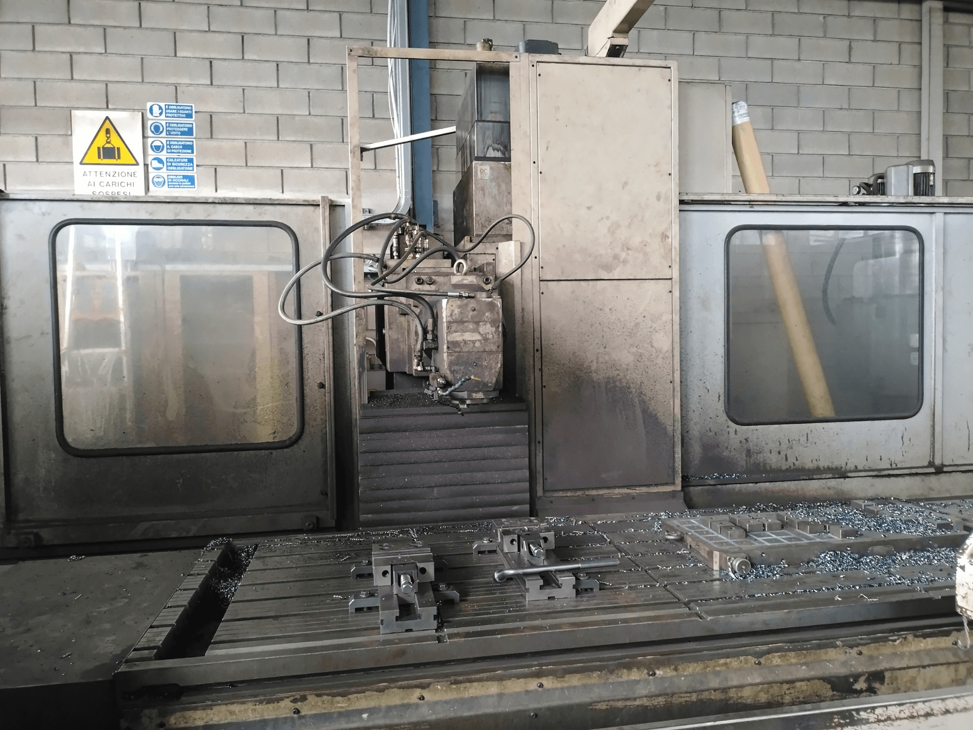 Lůžková frézka TIGER TFA6 v dílně, pohled zepředu ukazuje nástroje a kovové hobliny na stole.