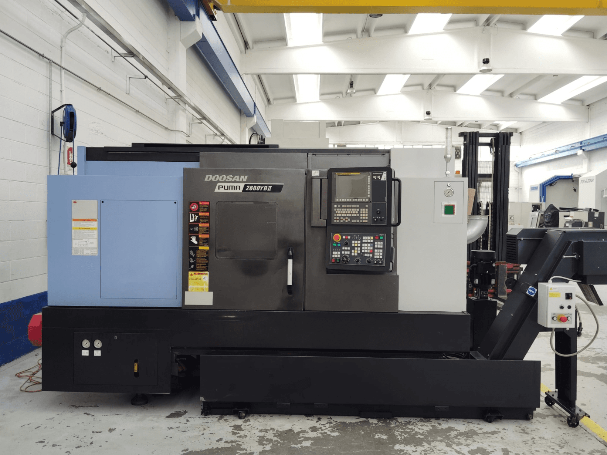 Pohled zepředu na horizontální soustruh DOOSAN Puma 2600YB II s viditelným ovládacím panelem a bezpečnostními štítky.