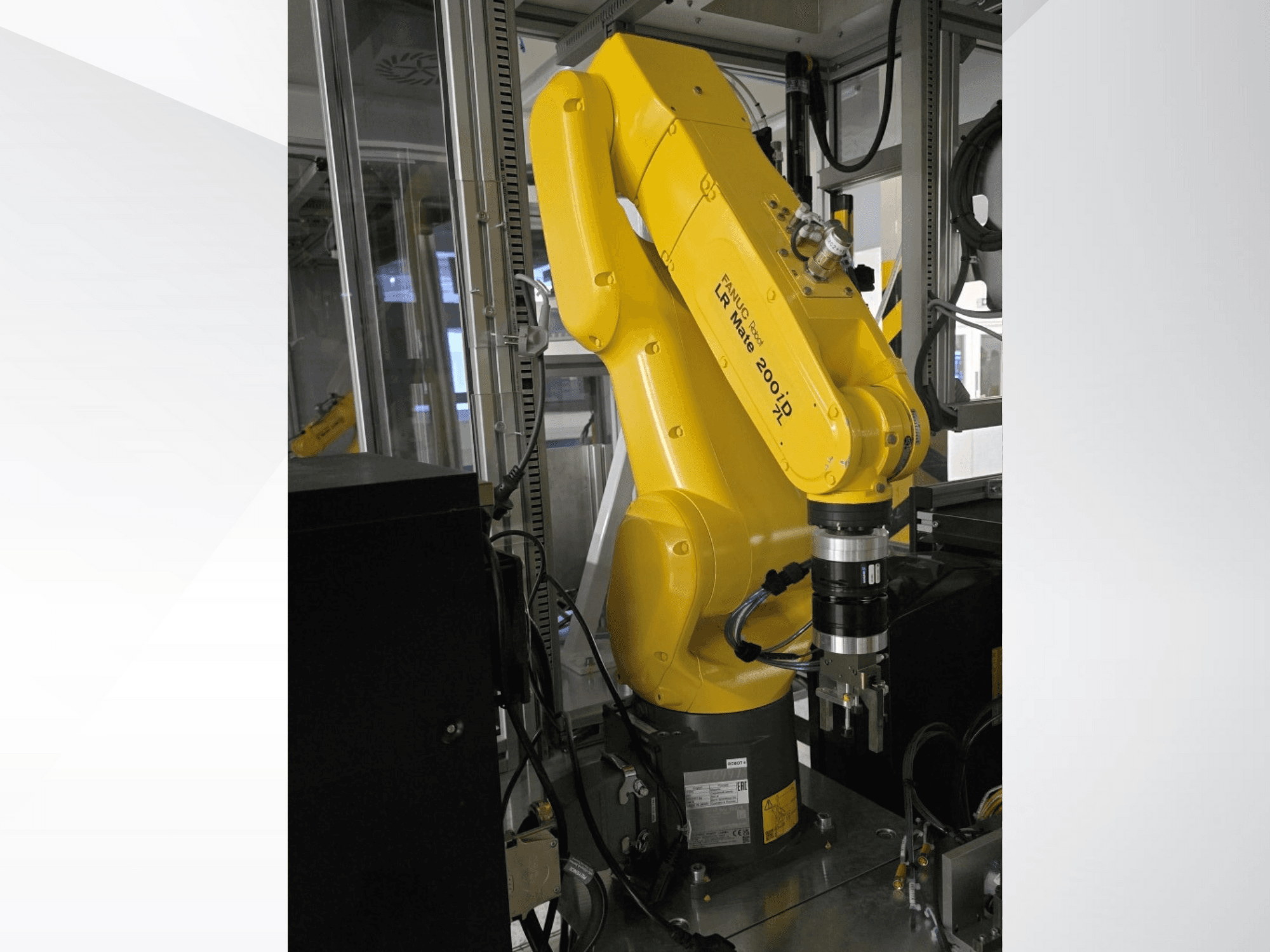 Žluté robotické rameno Fanuc LR Mate 200iD zobrazené z bočního pohledu, s chapadlem a různými připojenými kabely.