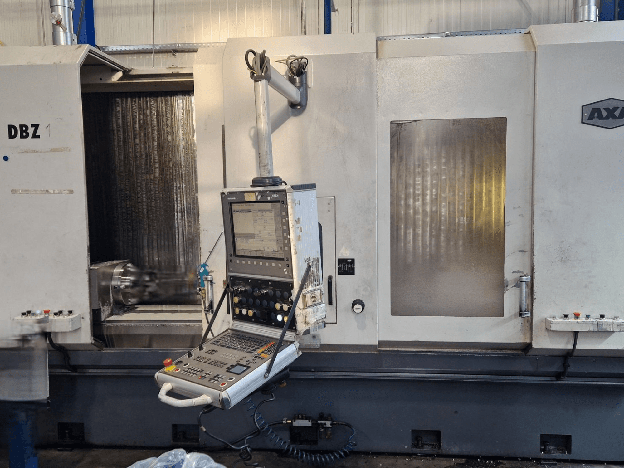 Vertikální obráběcí centrum AXA DBZ zobrazené z úhlového čelního pohledu, s ovládacím panelem a viditelným prostorem pro řezné nástroje.