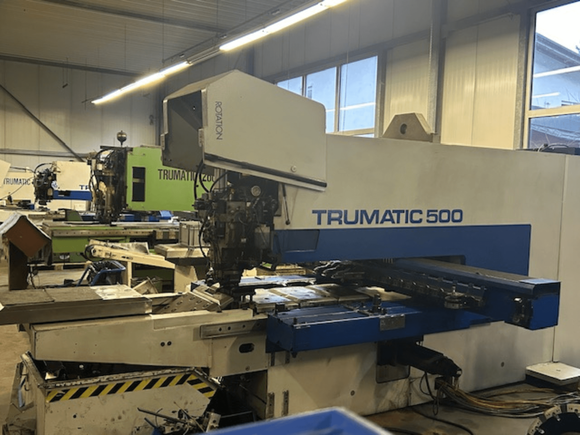 Děrovací stroj TRUMPF TRUMATIC 500 CNC, pohled zepředu, ovládací panel a mechanické části. Prostředí průmyslové dílny.