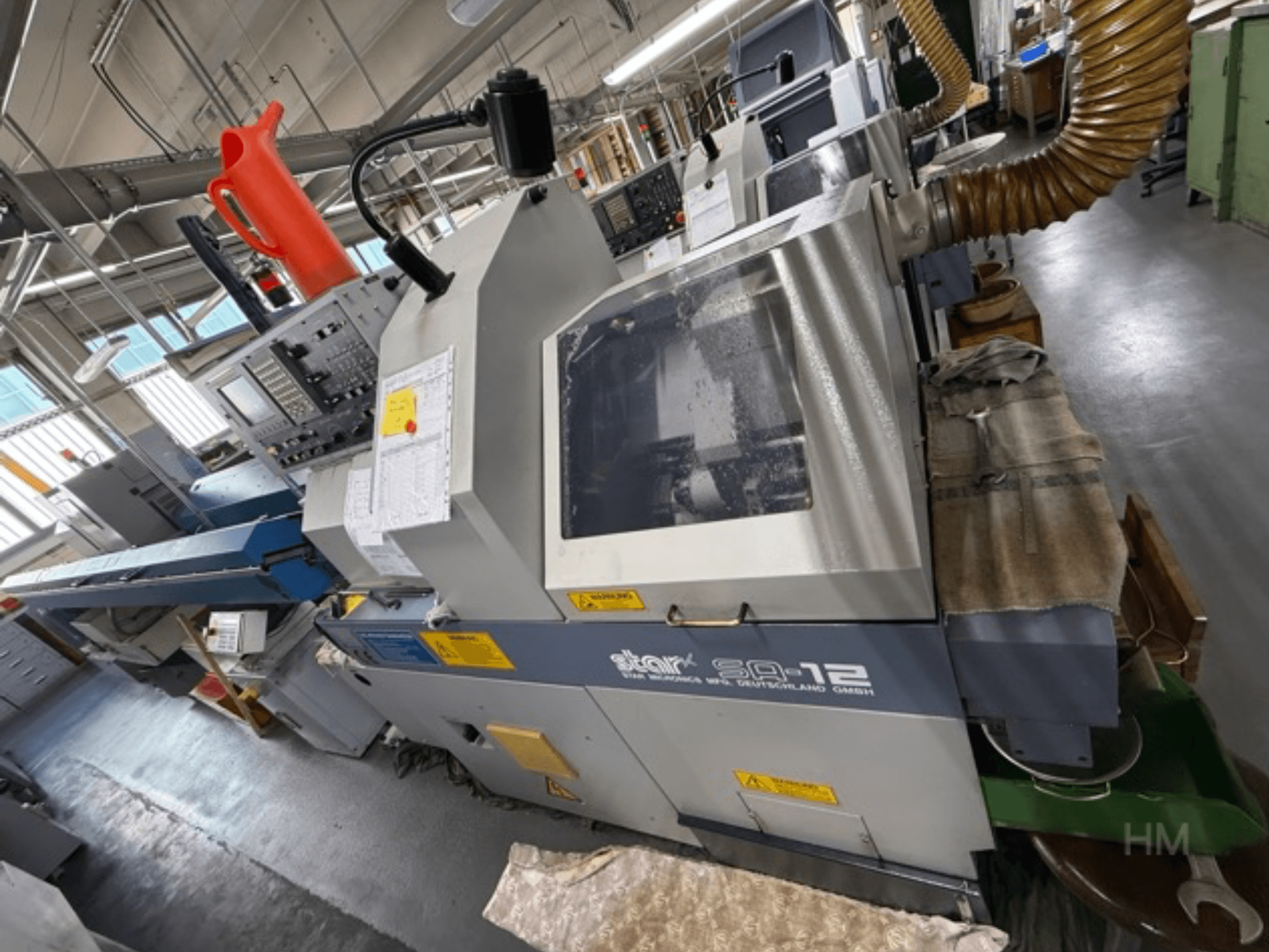 Obráběcí centrum Star SQ-12, boční pohled s viditelným ovládacím panelem, nádobou na chladicí kapalinu a hadicí pro odsávání prachu.