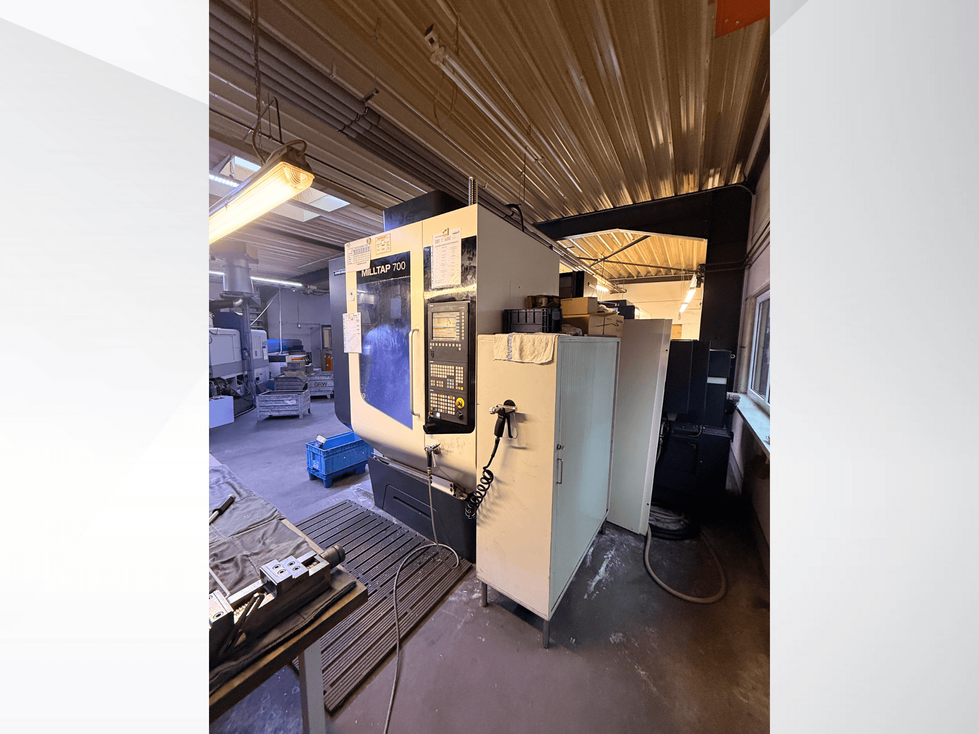 Stroj Milltap 700 CNC v dílně; pohled zepředu ukazuje ovládací panel, stojany na nástroje a úložné prostory s osvětlením nad nimi.