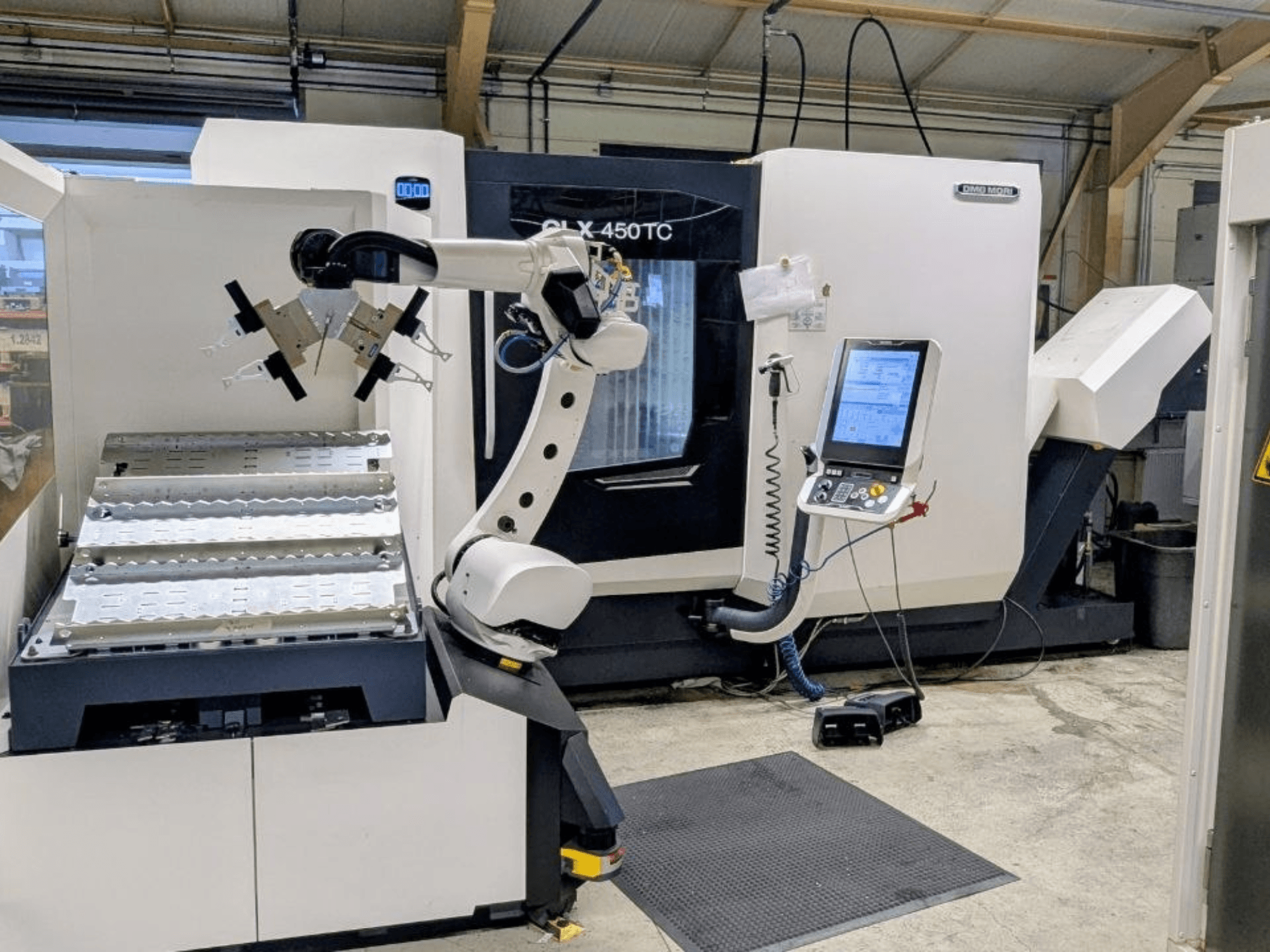 DMG MORI CLX 450 TC s Robo2go, pohled zepředu, na snímku je vidět robotické rameno a ovládací panel vedle stroje.