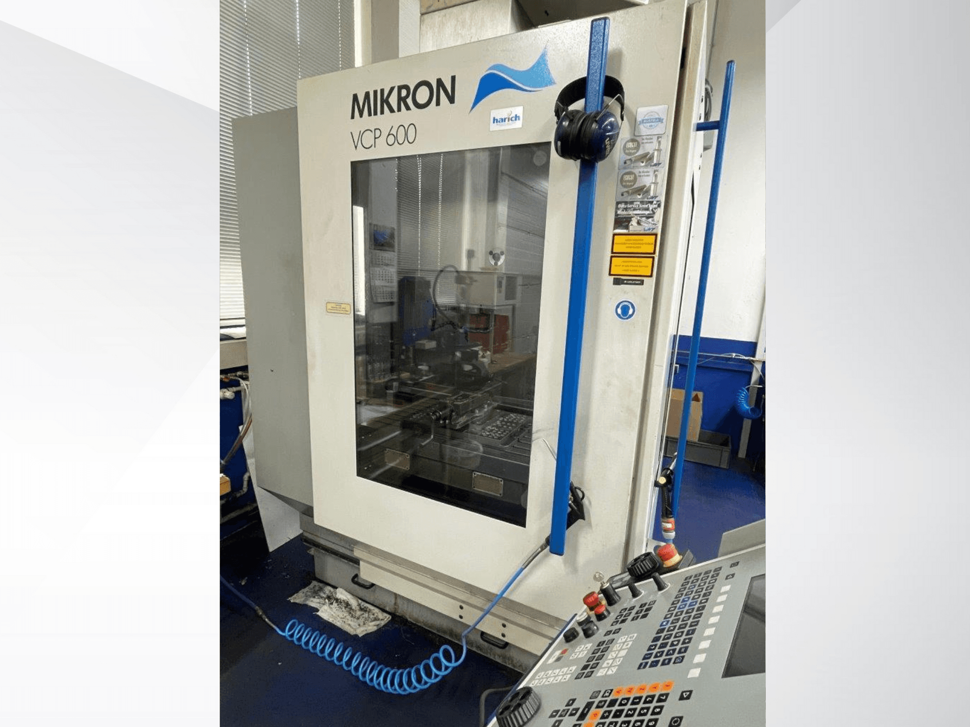 CNC stroj Mikron VCP 600, pohled zepředu, ovládací panel s tlačítky a viditelný obráběcí prostor za sklem.
