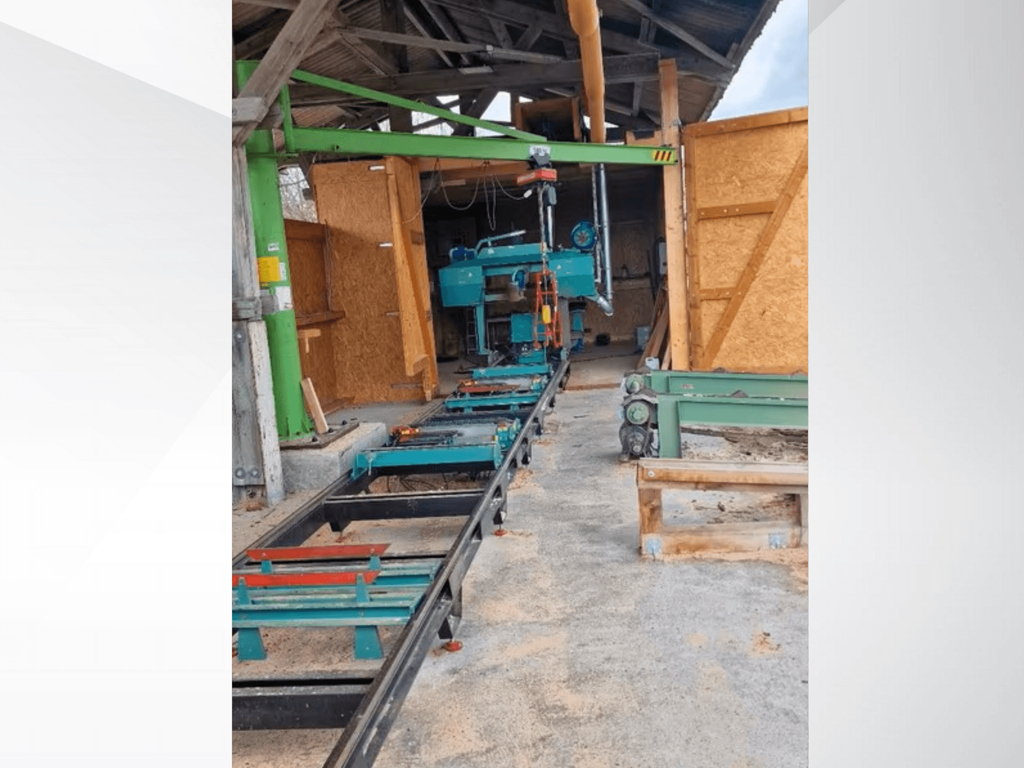 Horizontální pásová pila v dílně, pohled zepředu. Součástí vybavení je pás a další zelené příslušenství.