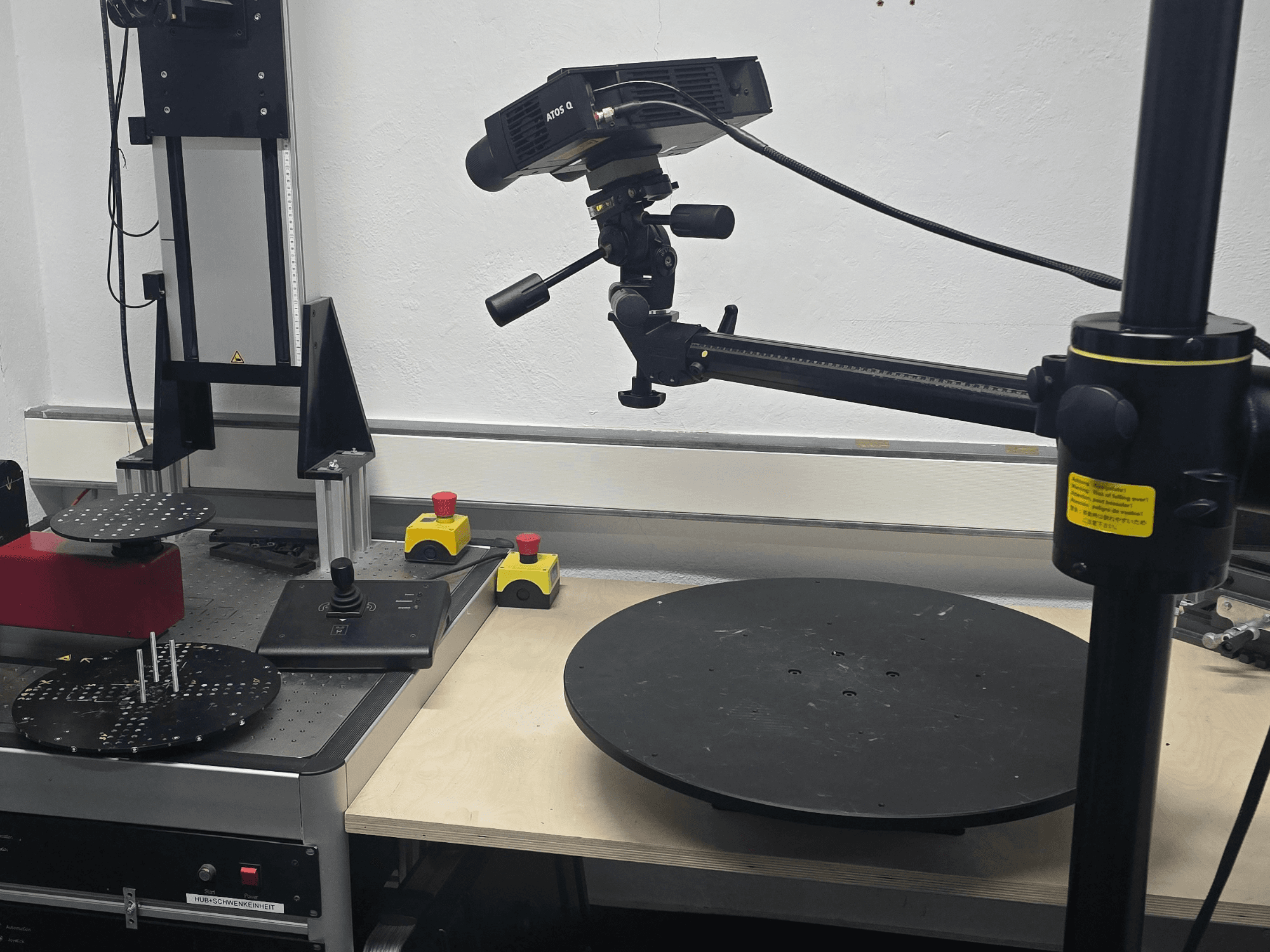 Pohled zepředu na optický měřicí stroj ZEISS ATOS Q 12M, vybavený skenovací hlavou, ovládacím panelem a otočnou kruhovou plošinou.