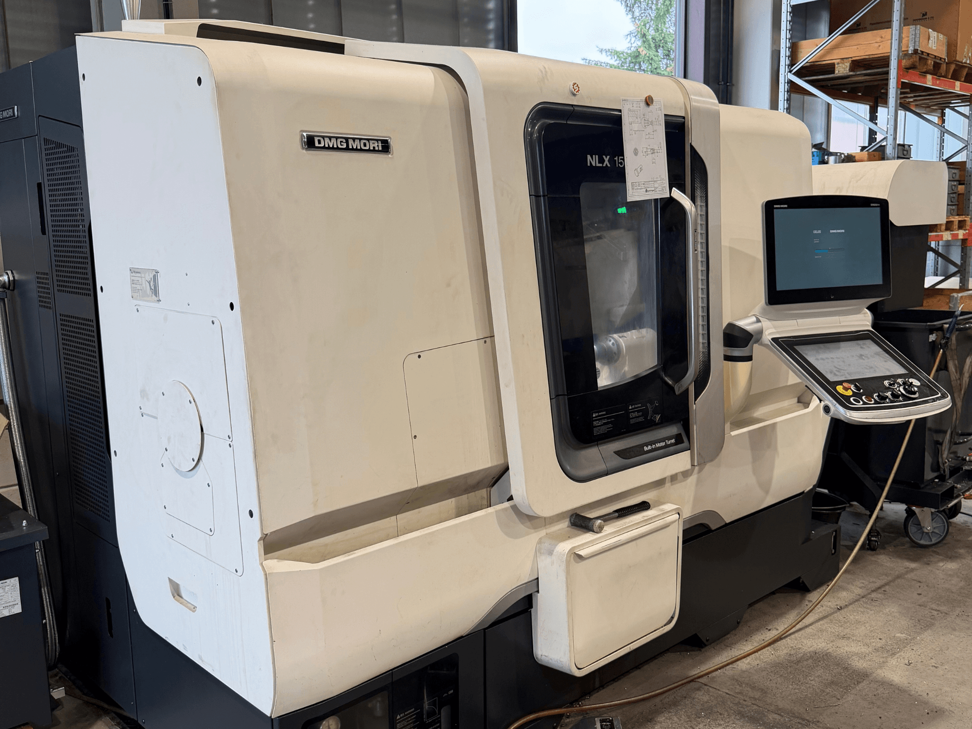 Pohled zepředu na horizontální soustruh DMG MORI NLX1500MC/500, na kterém je přes průhledný kryt vidět ovládací panel a oblast vřetena.