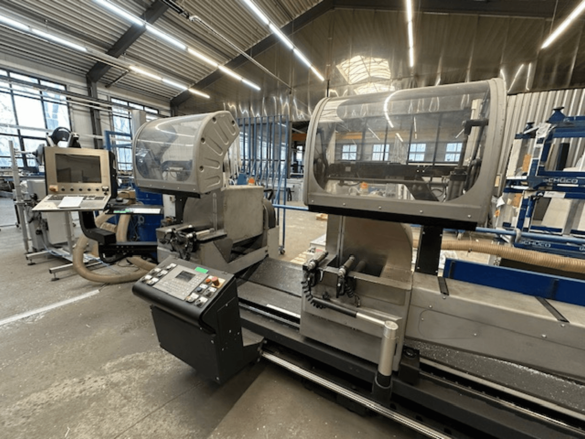 Kotoučová pila na kov SCHÜCO PDG E CUT, pohled zepředu, s ovládacím panelem, ochrannými kryty a řeznou plochou v dílenském prostředí.