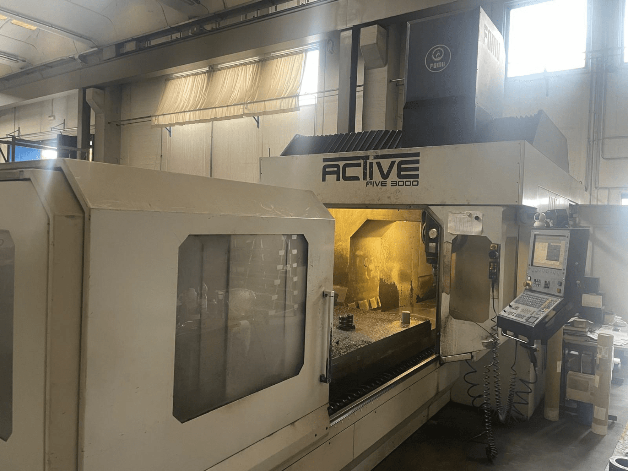 Pohled zepředu na CNC stroj ACTIVE Five 3000, zobrazující ovládací panel a pracovní prostor s částečně obrobeným dílem uvnitř.
