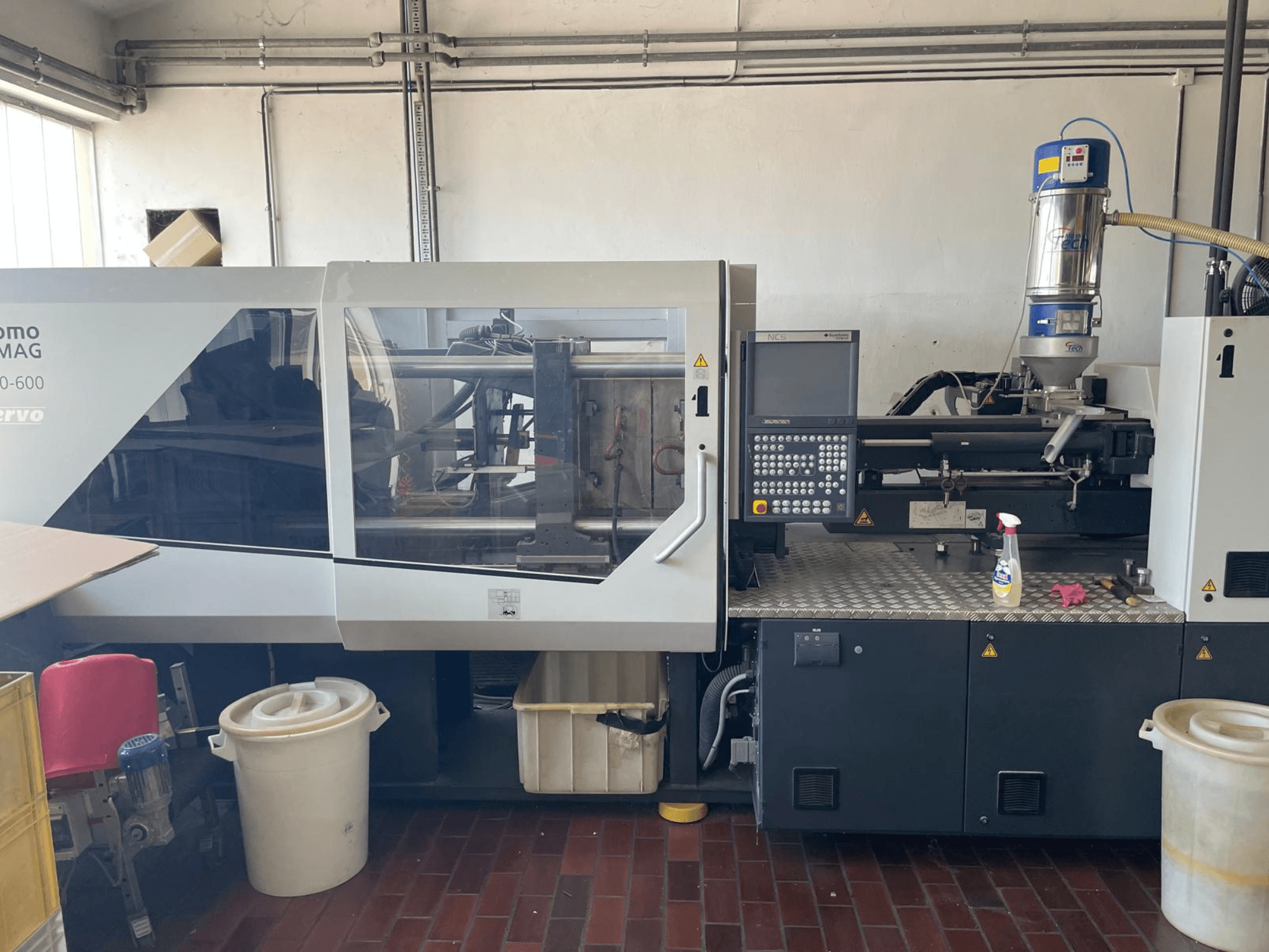 Pohled zepředu na hydraulický vstřikovací stroj SUMITOMO SHI DEMAG Systec 160/520-600 s ovládacím panelem a podávací jednotkou.