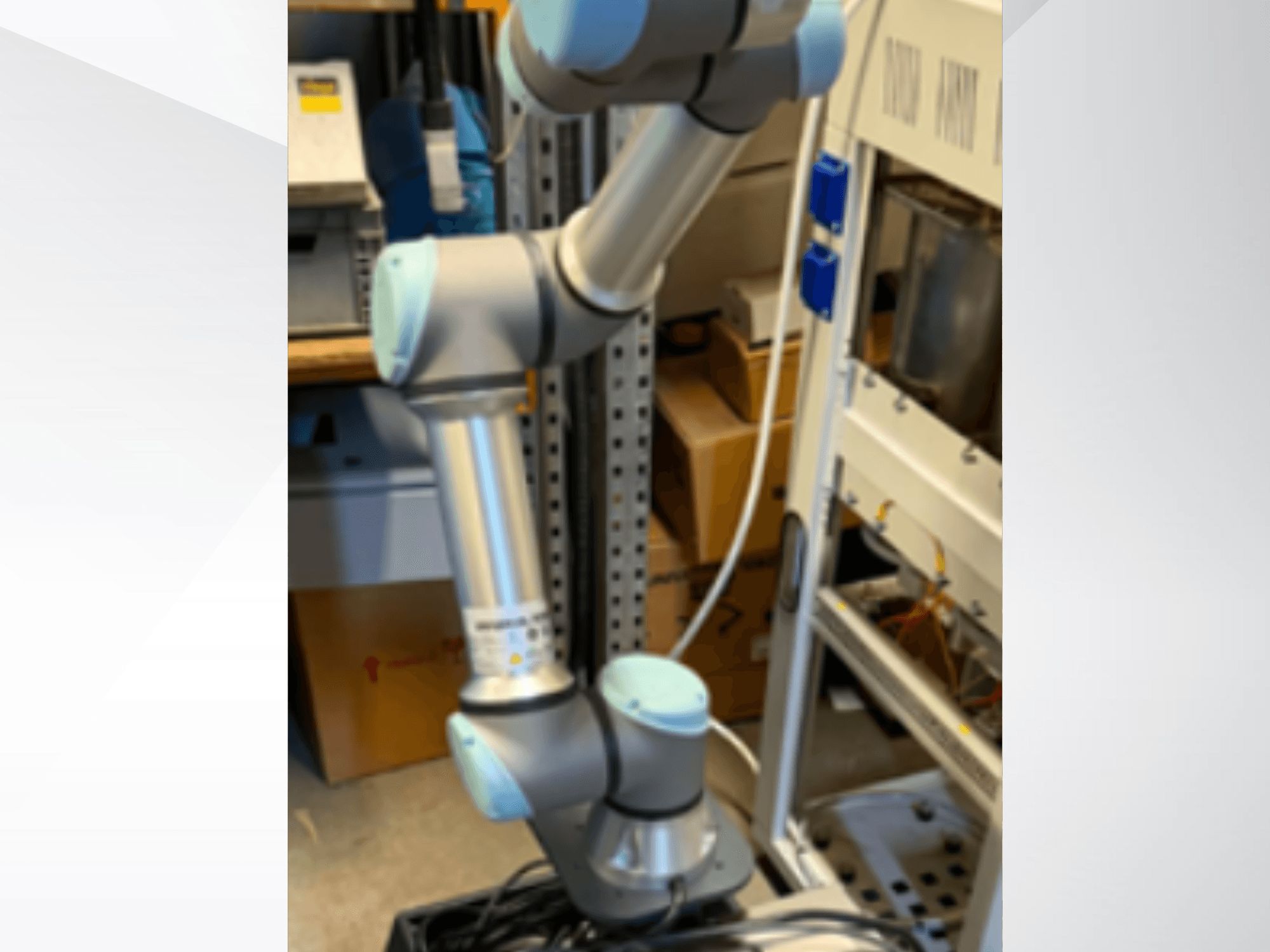 Robotické rameno UR5e od společnosti Universal Robots při pohledu z boku, na kterém jsou vidět kloubové spoje, lehká konstrukce a ovládací kabely.