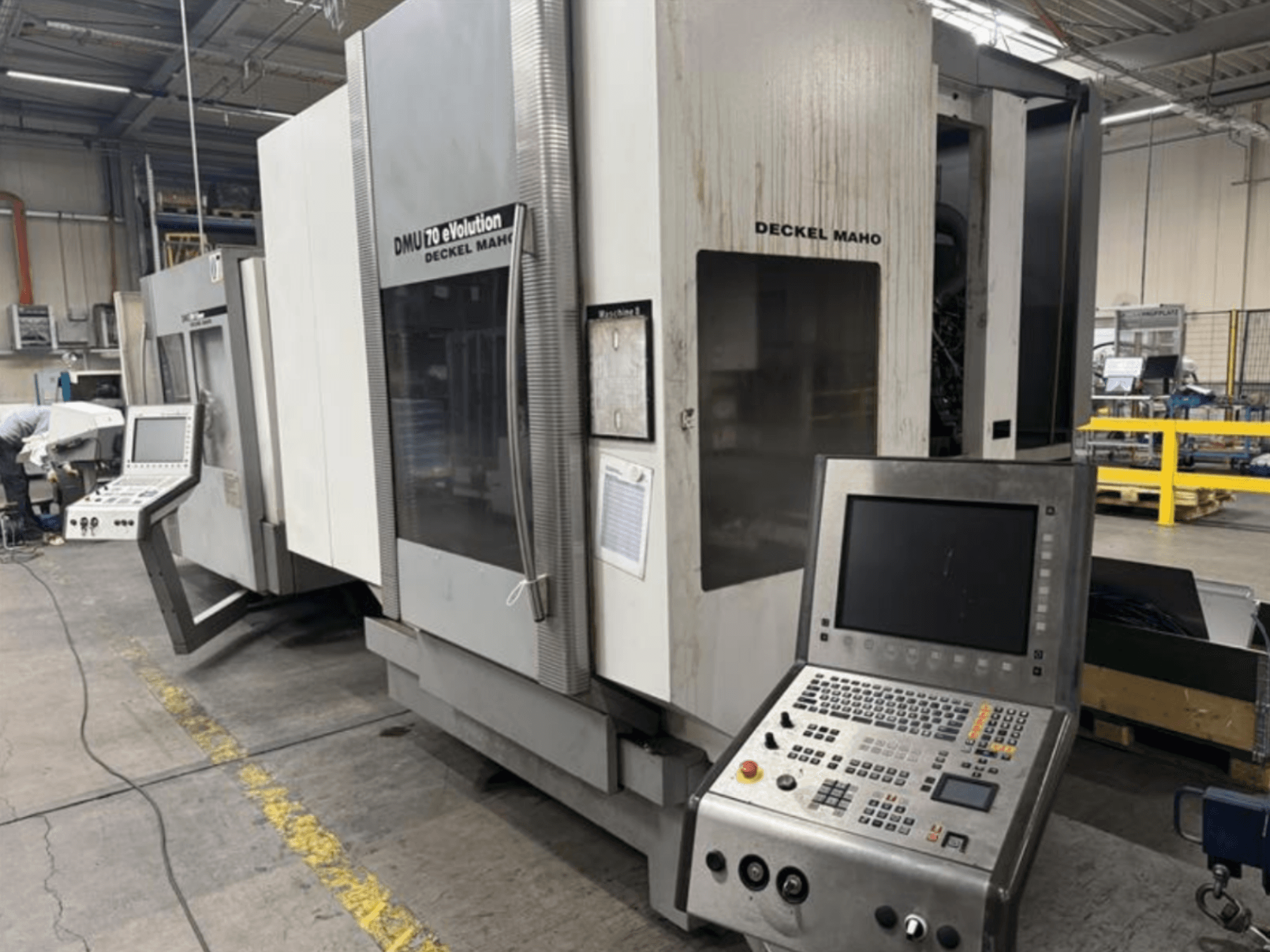 Pohled zepředu na CNC stroj Deckel Maho DMU 70 eVOLUTION s ovládacím panelem, umístěný ve výrobním závodě.