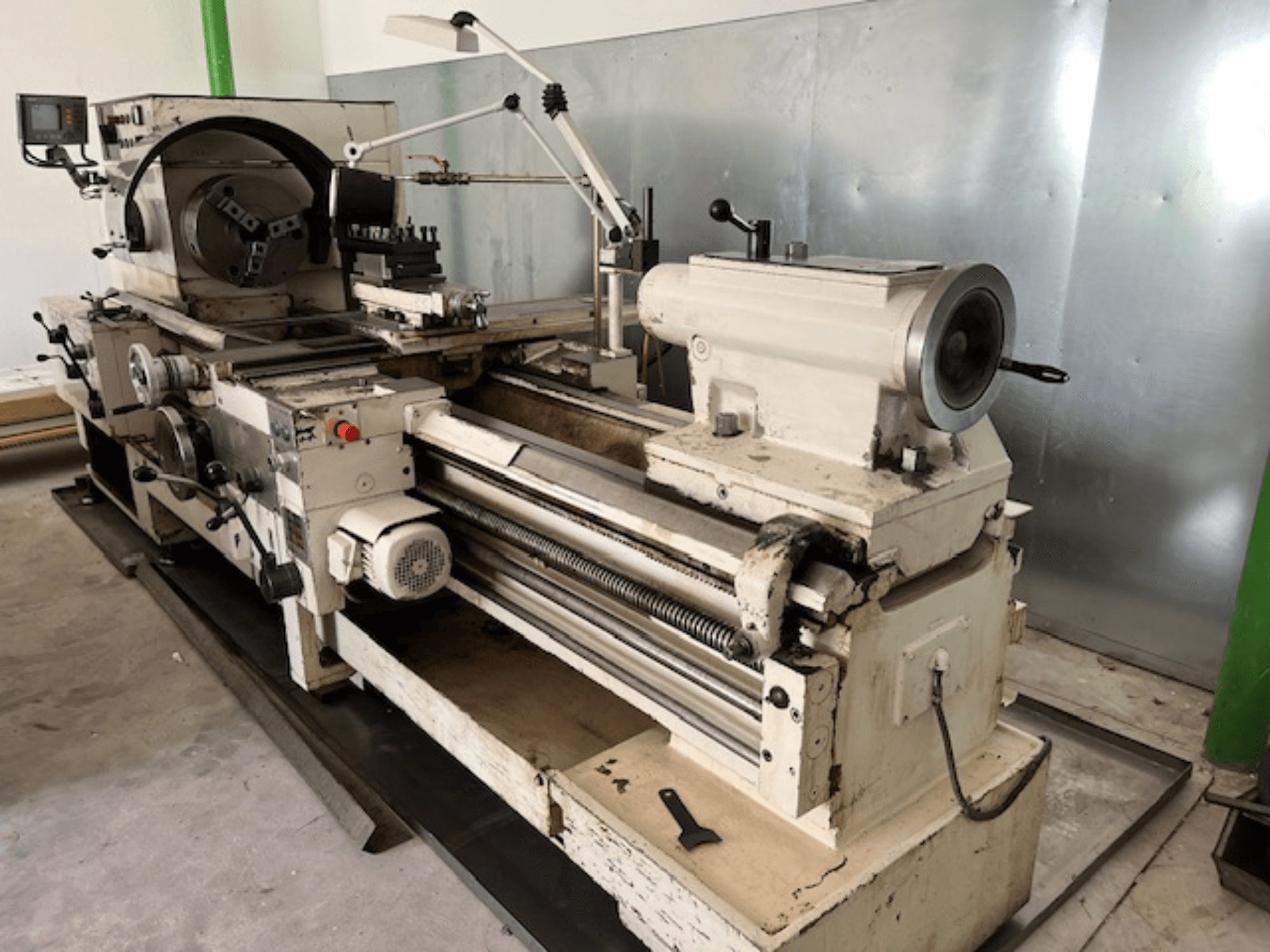 Starožitný soustruh na kov s ovládacím panelem a nástroji, boční pohled, znázorňující provozní prvky a povrchovou úpravu kovu.