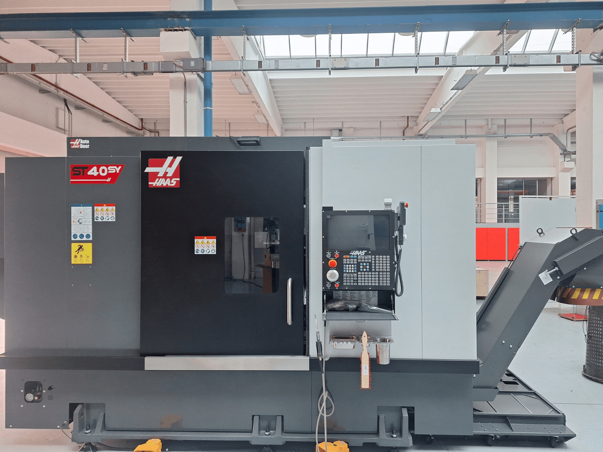 Horizontální soustruh Haas ST-40SY v bočním pohledu, na kterém je vidět ovládací panel a bezpečnostní štítky.