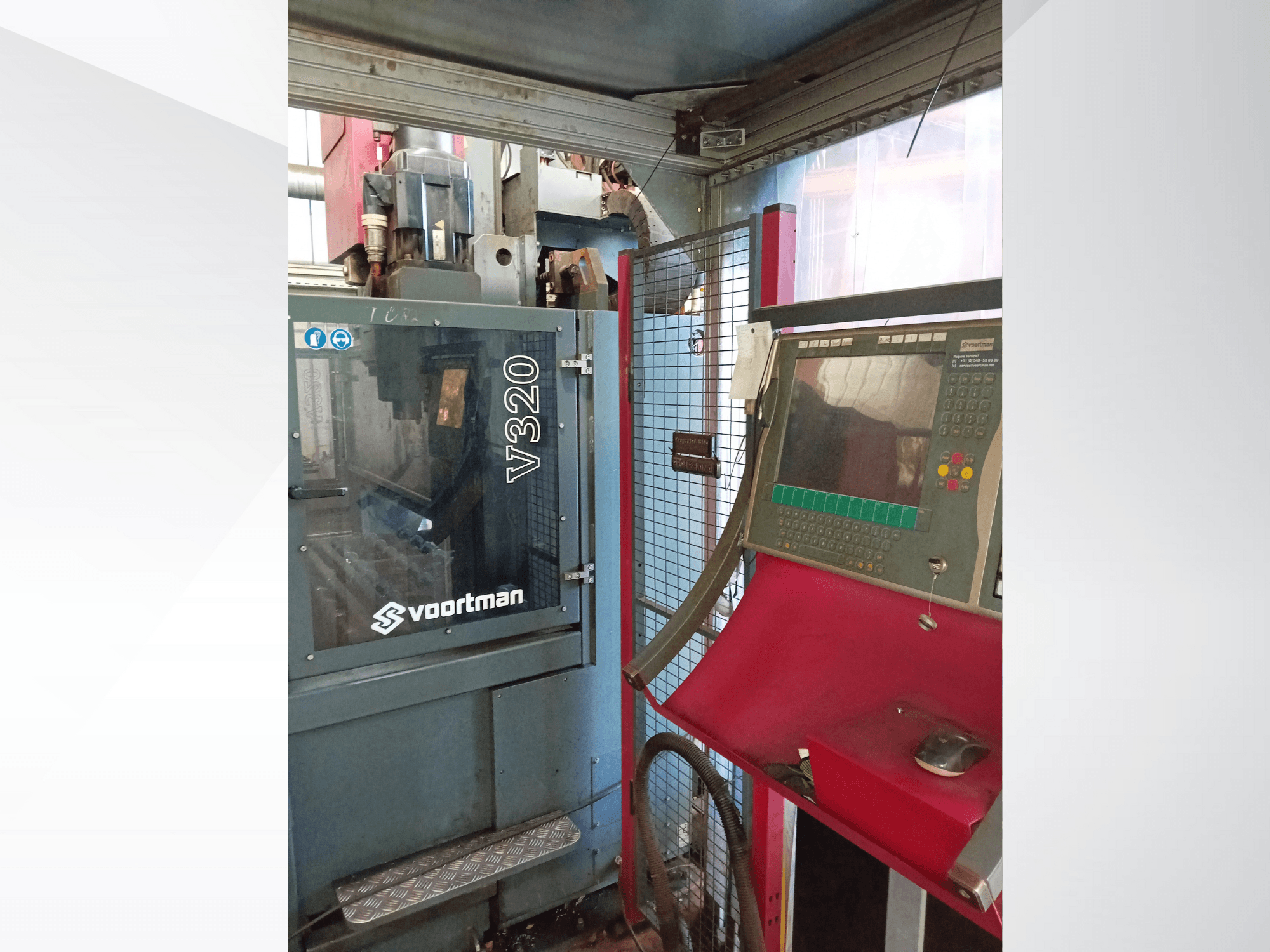 Pohled zepředu na CNC stroj Voortman V320, ovládací panel s tlačítky, obrazovka displeje a kryt z bezpečnostní sítě.