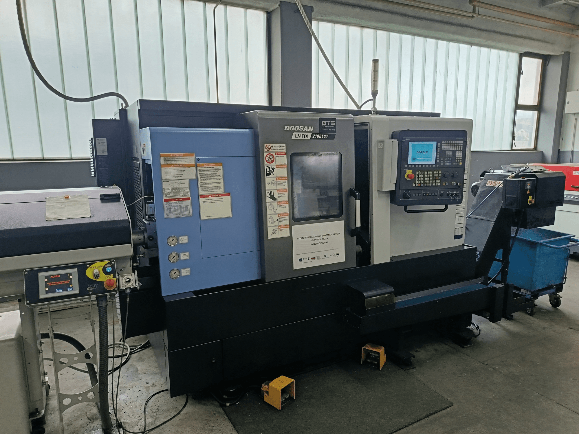 Otočné frézovací centrum DOOSAN LYNX 2100 LSY, boční pohled na ovládací panel a provozní tlačítka s viditelnými informačními štítky.