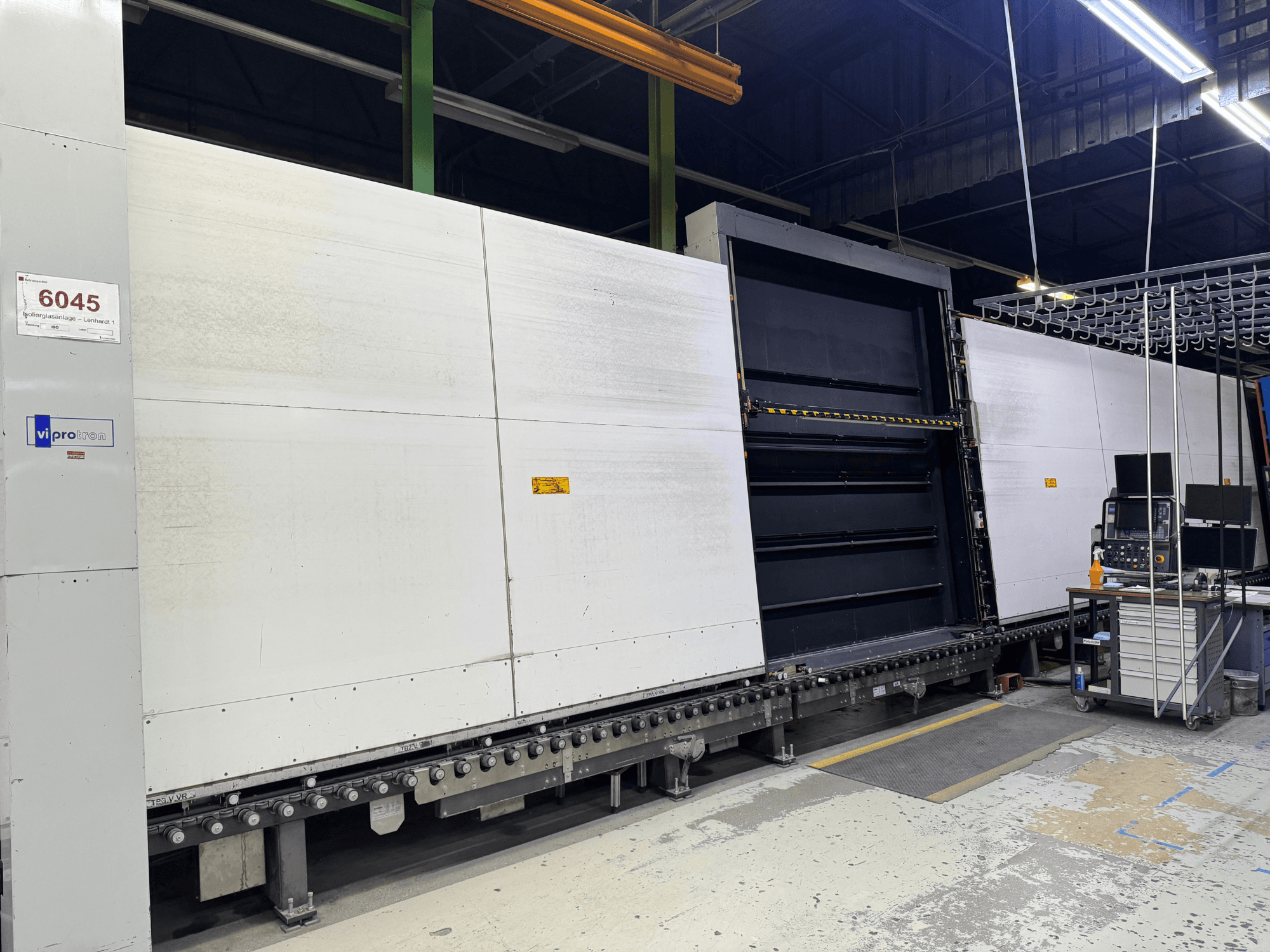 Pohled zepředu na lisovací stroj Vipro s otevřeným panelem, na kterém je vidět provozní vybavení a pracovní plocha vedle něj. Model 6045.