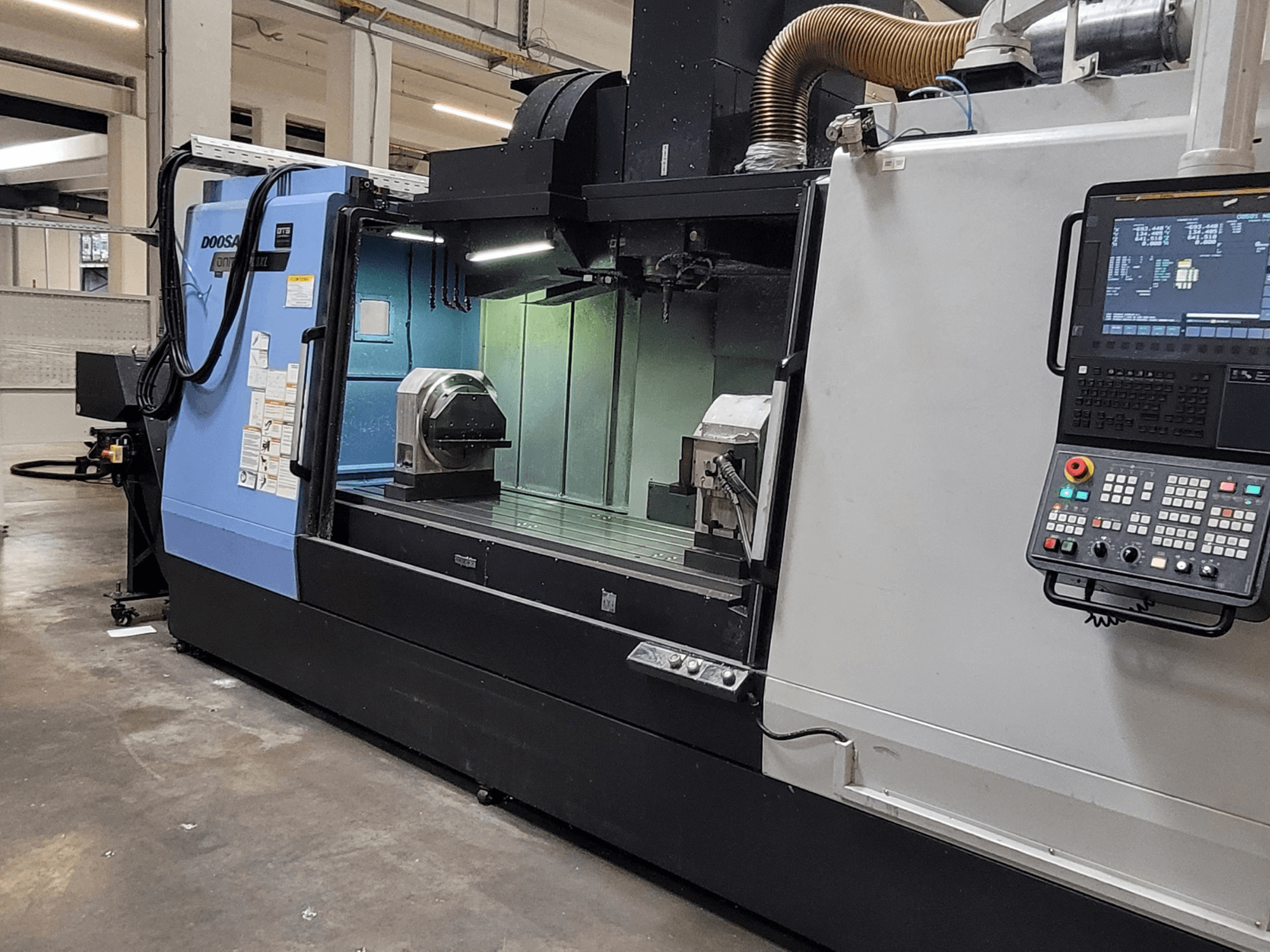 Vertikální obráběcí centrum DOOSAN DNM 6700 XL, pohled zepředu znázorňující ovládací panel, pracovní stůl a obráběcí prostor.