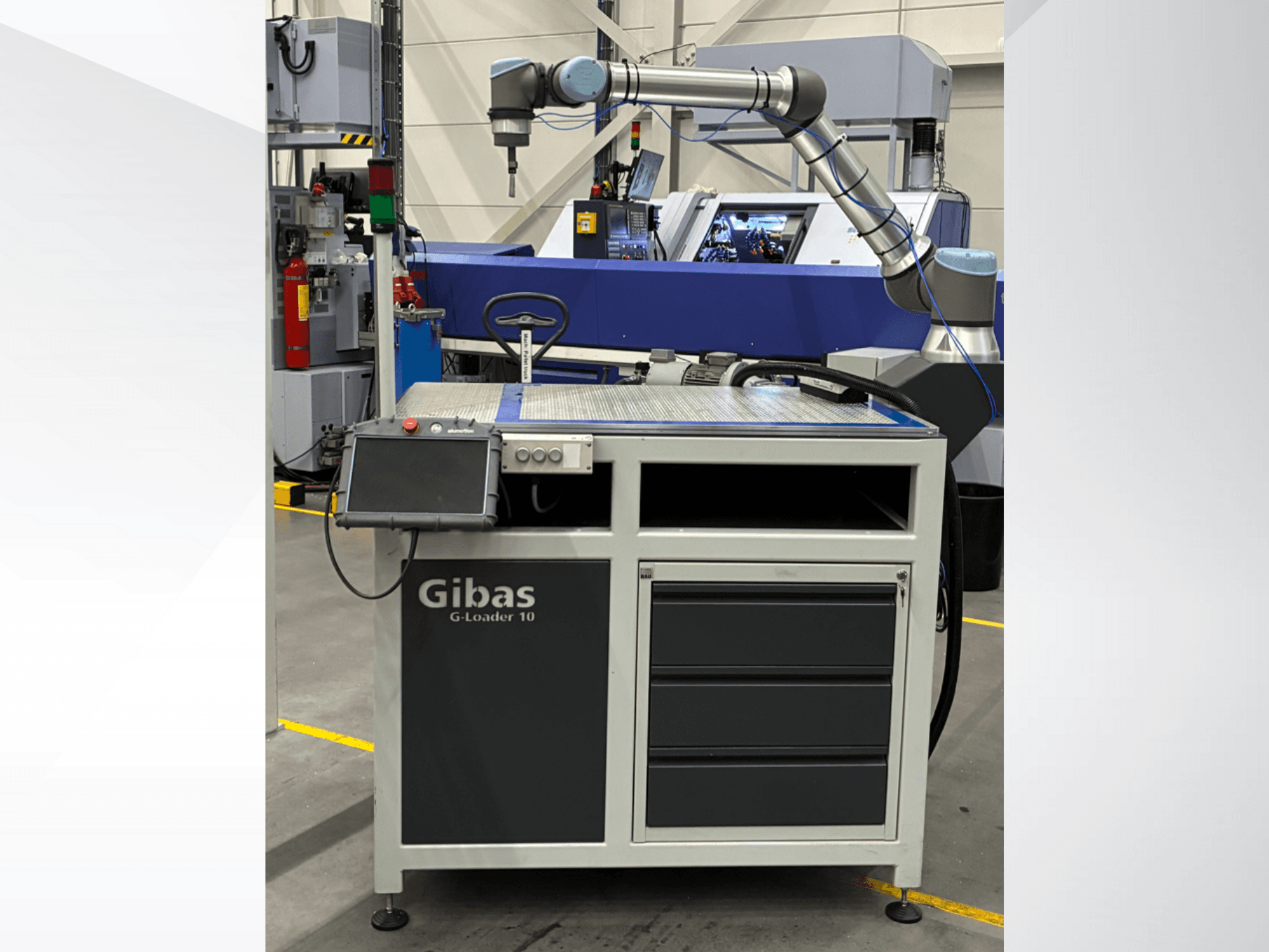 Nakladač Gibas G-Loader 10 s robotickým ramenem, pohled zepředu; s dotykovým ovládáním a zásuvkou v průmyslovém prostředí.