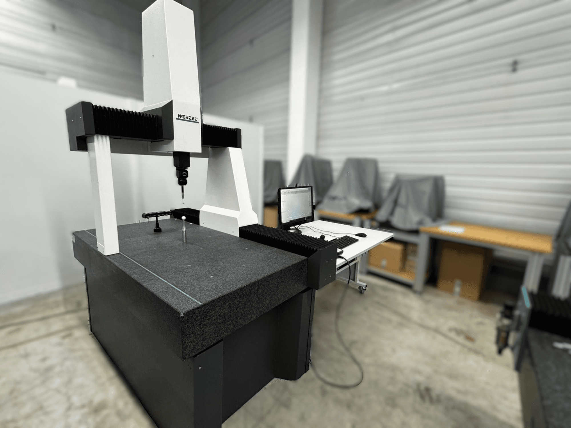 Souřadnicový měřicí stroj Wenzel LH 54 v bočním pohledu, se sondou a počítačovým rozhraním na šedém podstavci.