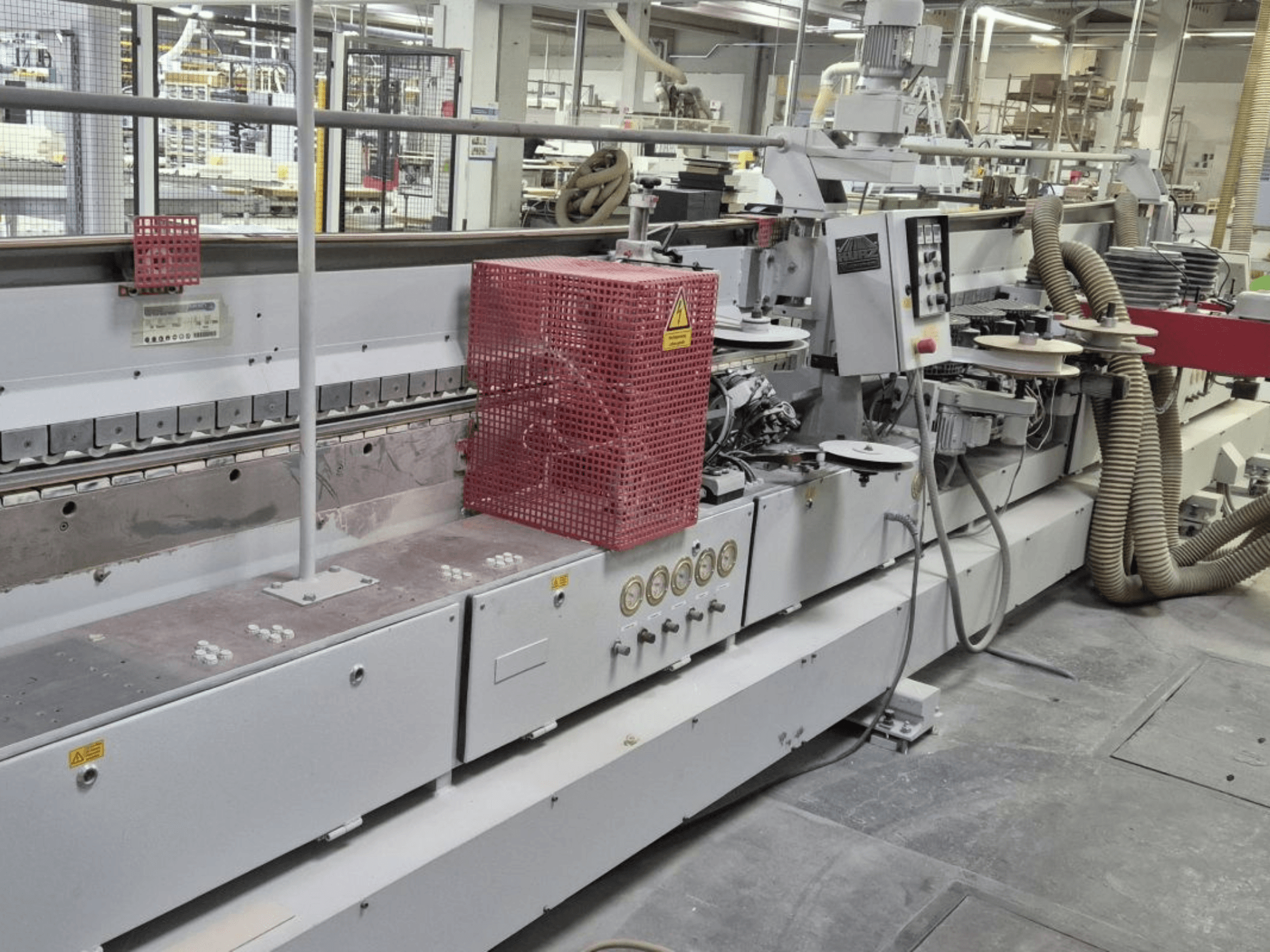 Olepovačka hran s ovládacím panelem, sacími hadicemi a červeným bezpečnostním krytem, pohled z boku.