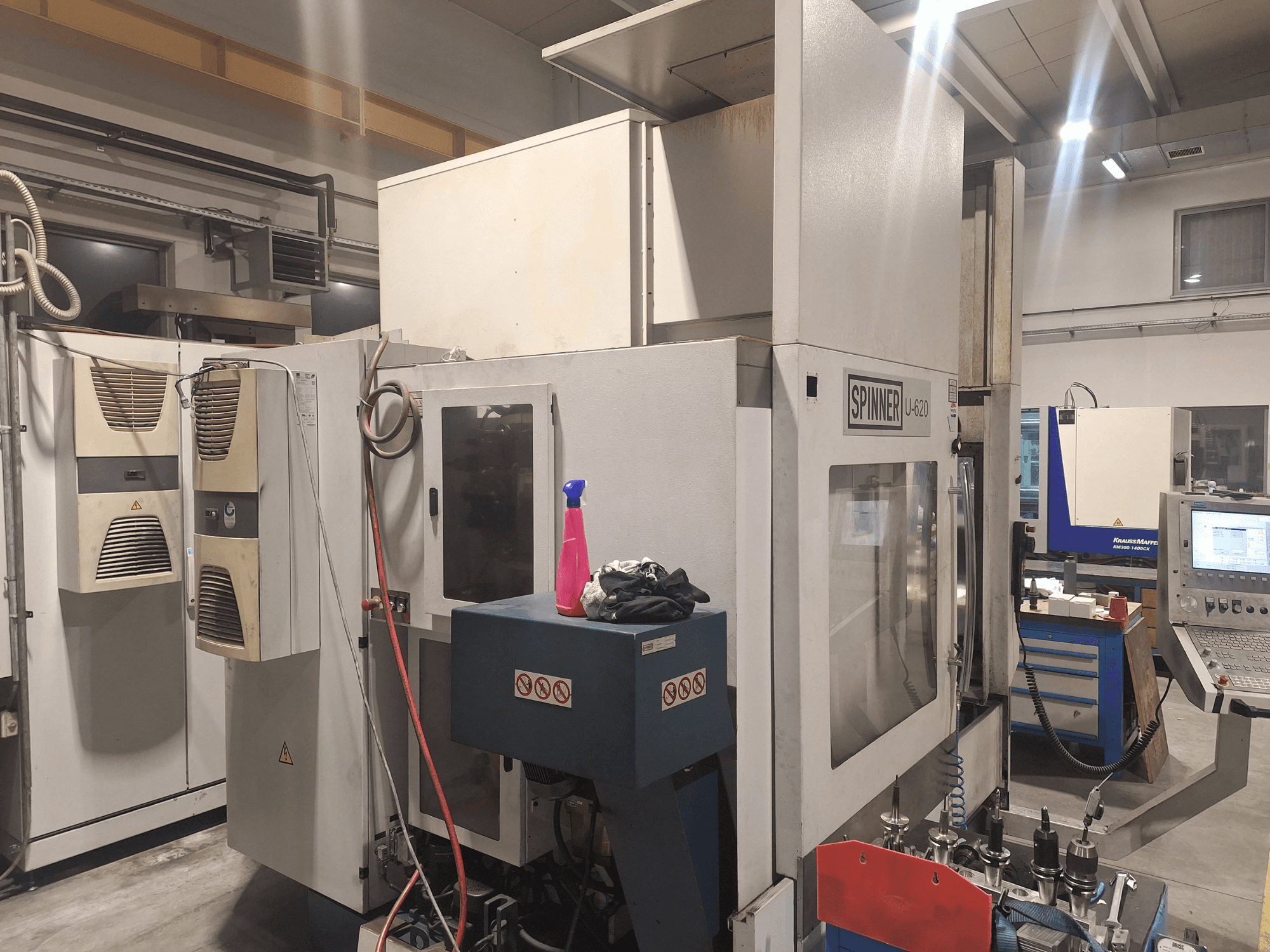Stroj Spinner U-620 CNC zobrazený zepředu v dílně, s ovládacím panelem a různými nástroji na pracovním stole poblíž.