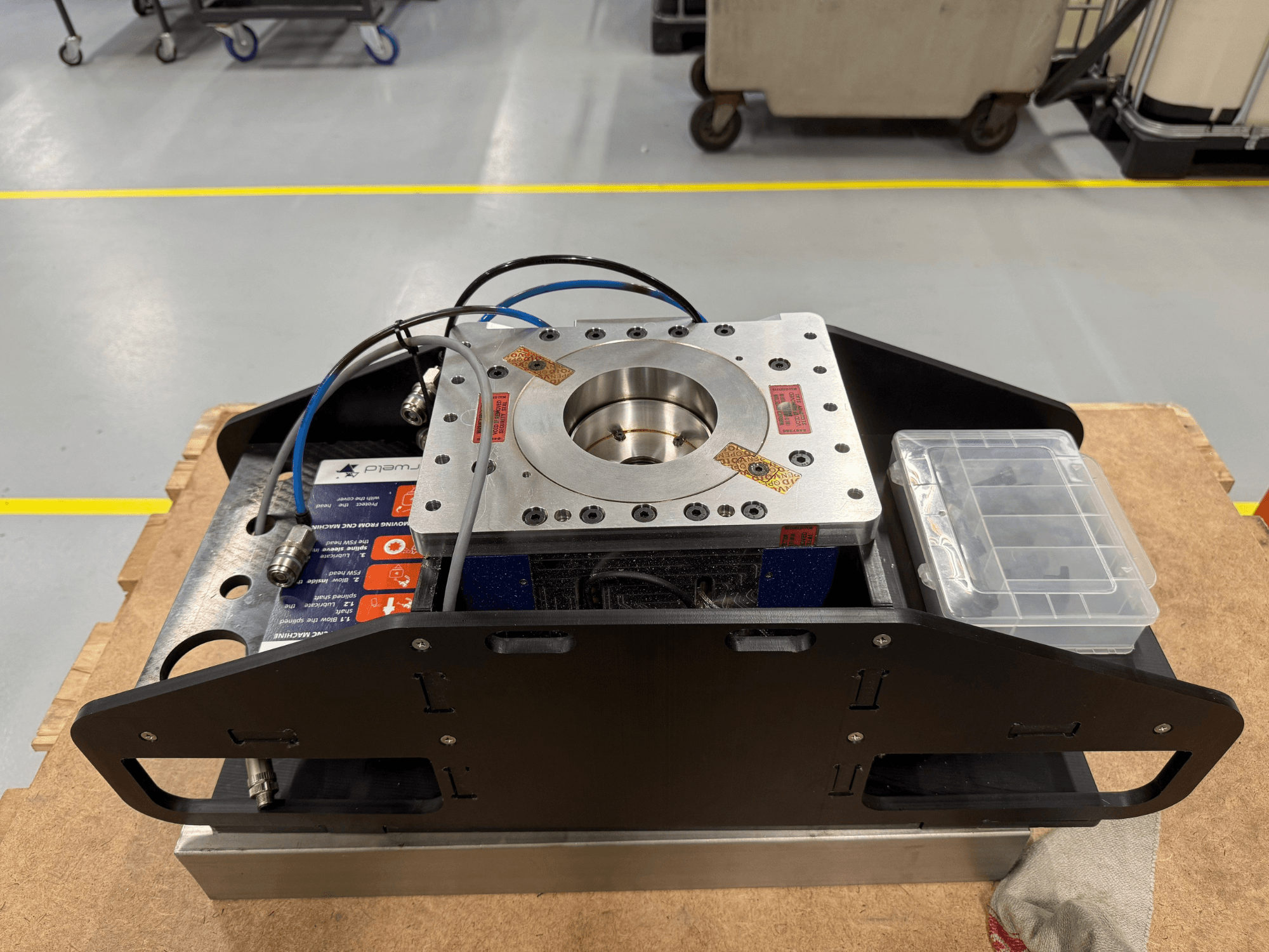 Obráběná kovová součástka s modrými kabely, pouzdrem na příslušenství a plochou základnou, zobrazená z horního pohledu, ideální pro mechanické aplikace.