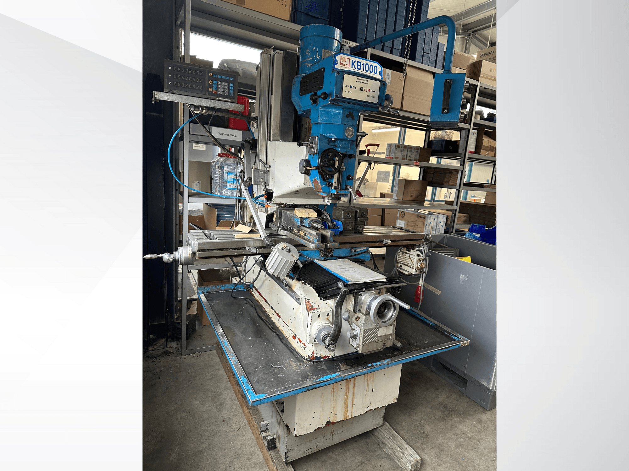 Vertikální frézka KB1000 s digitálním displejem, boční pohled na stůl, vřeteno a držák nástrojů.