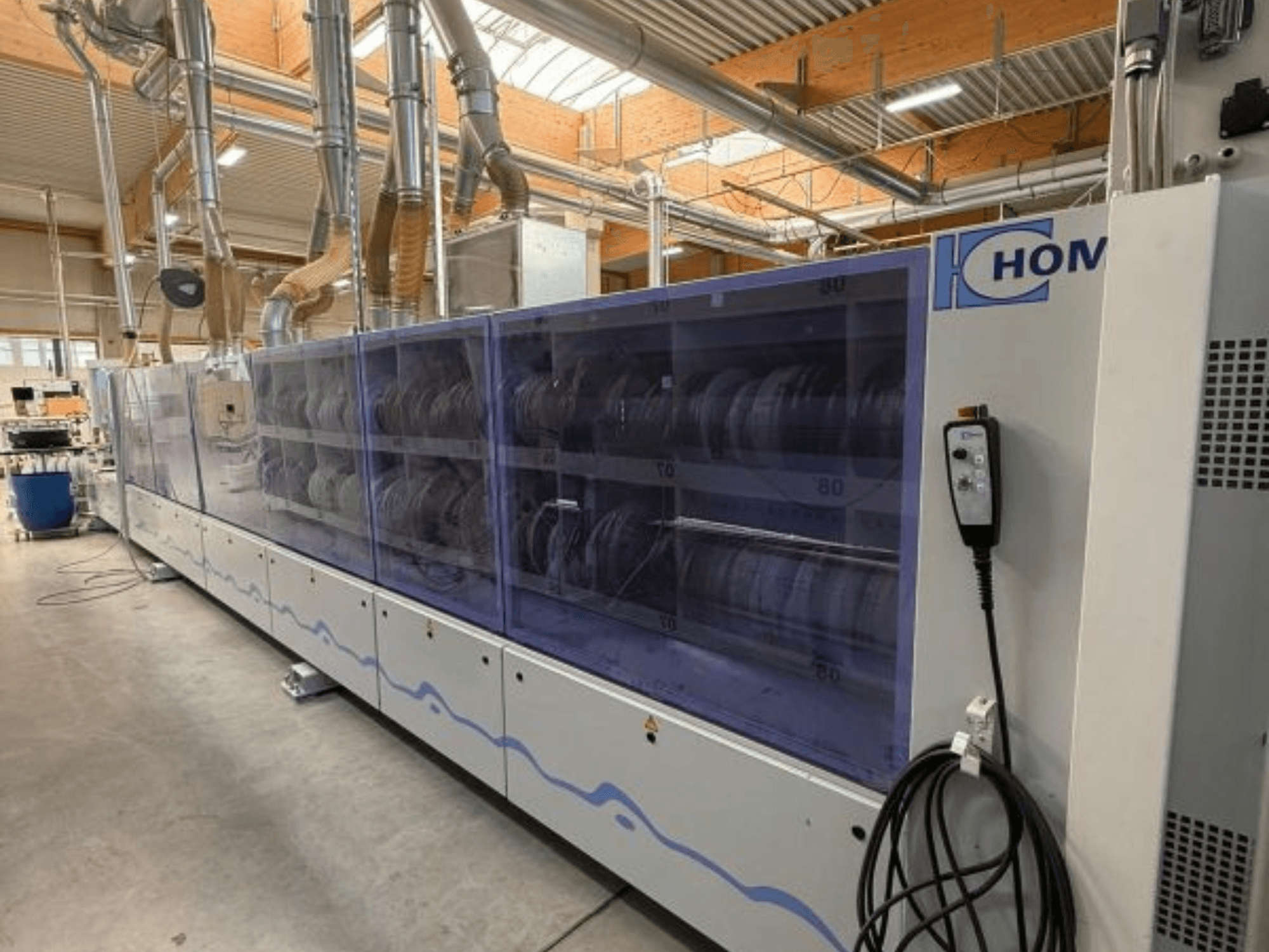 Průmyslová myčka HOM, pohled zepředu, s průhledným panelem s nádobím; ovládací panel s tlačítky na boku.