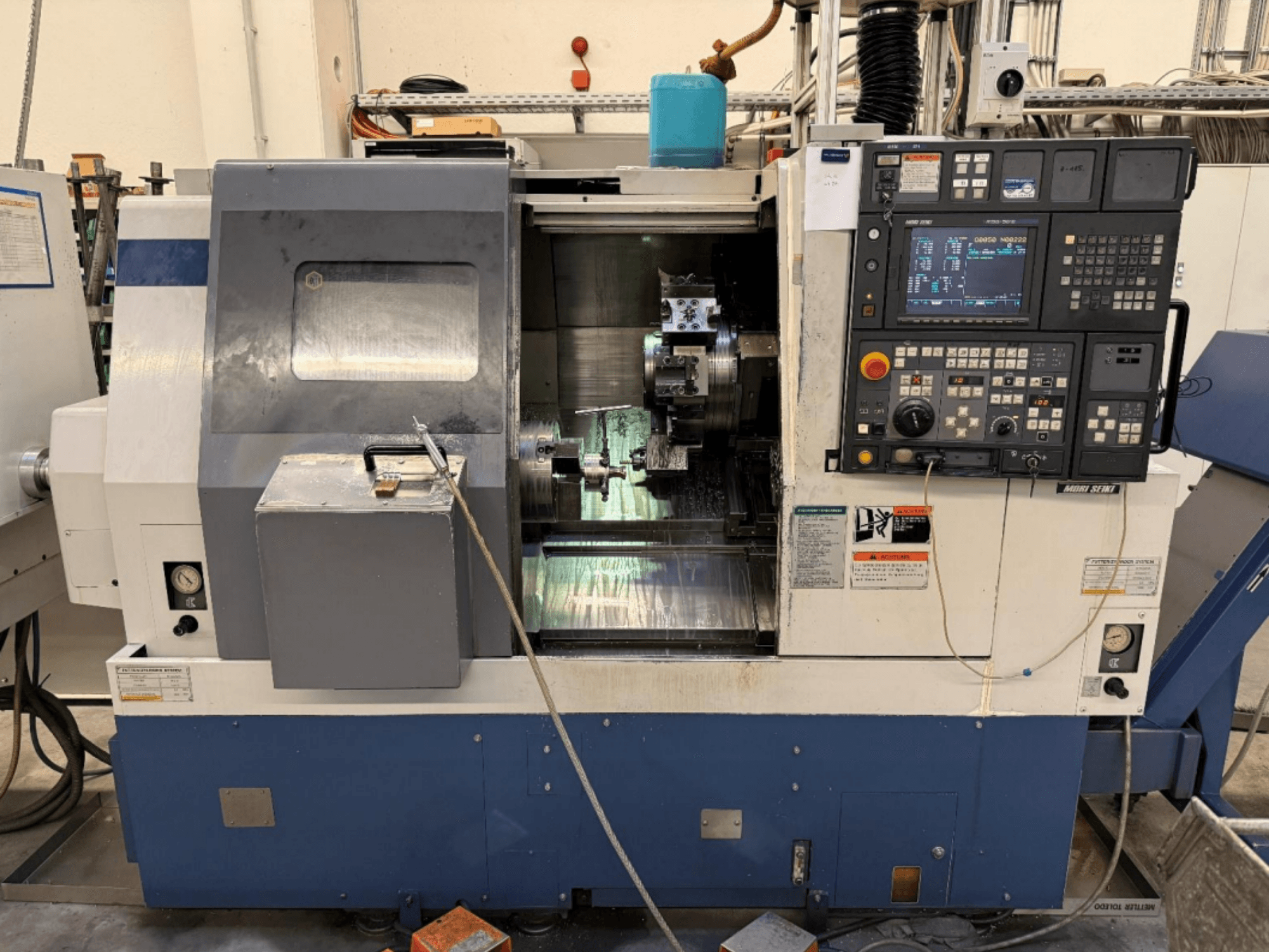 Soustružnicově-frézovací centrum MORI SEIKI SL-250ASMC, pohled zepředu znázorňující ovládací panel a upínací sklíčidlo obrobku v provozu.