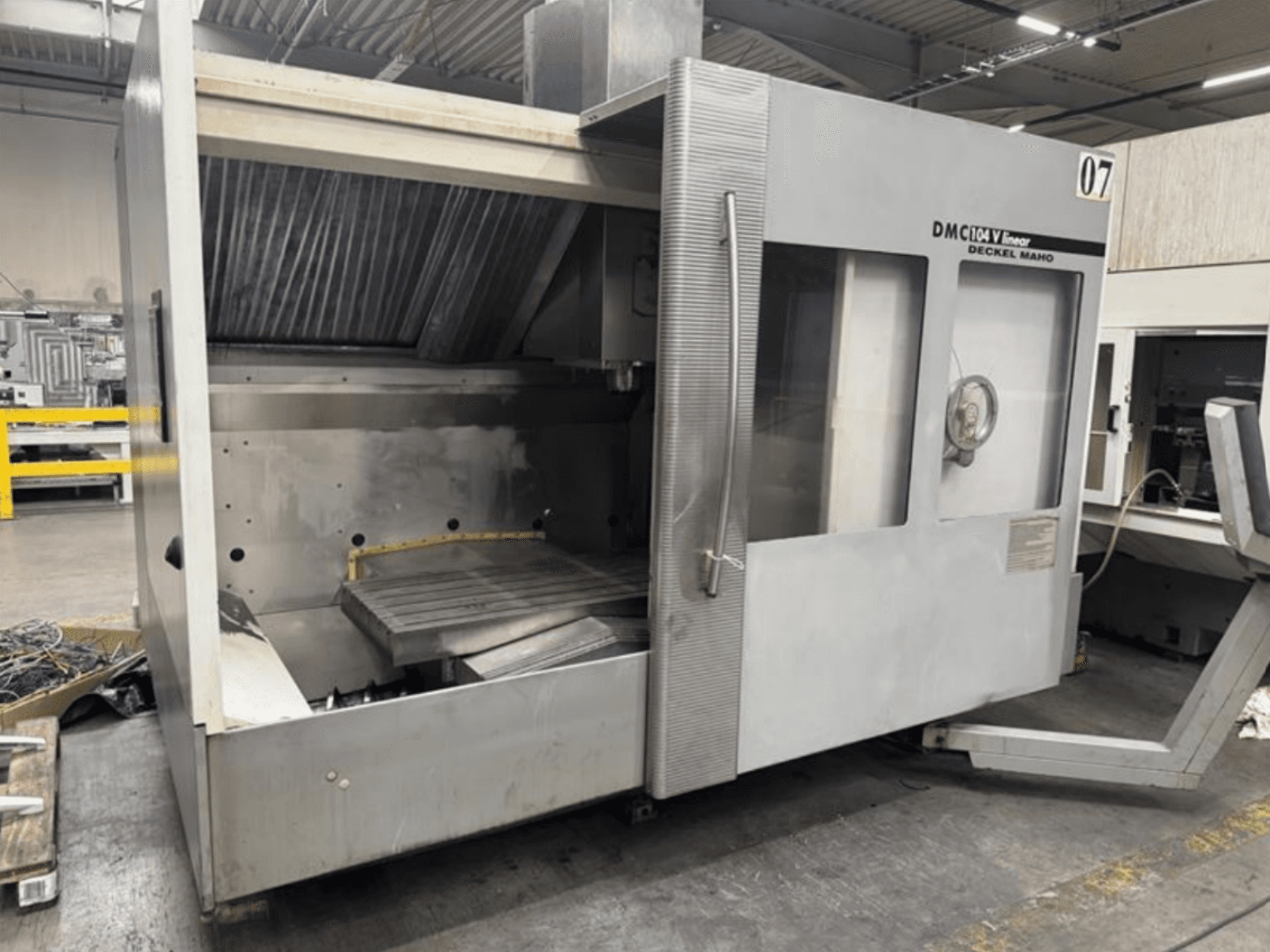 Lineární stroj DMC 104 V od společnosti Deckel Maho, pohled zepředu, s prázdným obráběcím prostorem s velkým pracovním stolem.