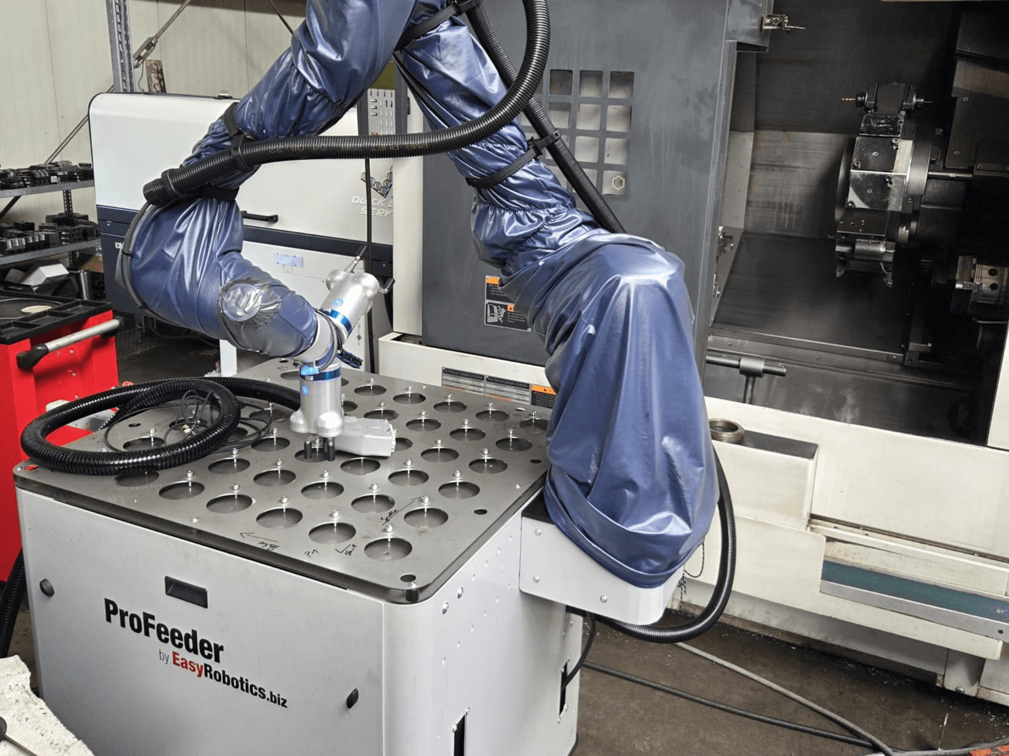 Kolaborativní robot EASYROBOTICS ProFeeder z čelního pohledu s robotickým ramenem umístěným nad perforovaným kovovým stolem.