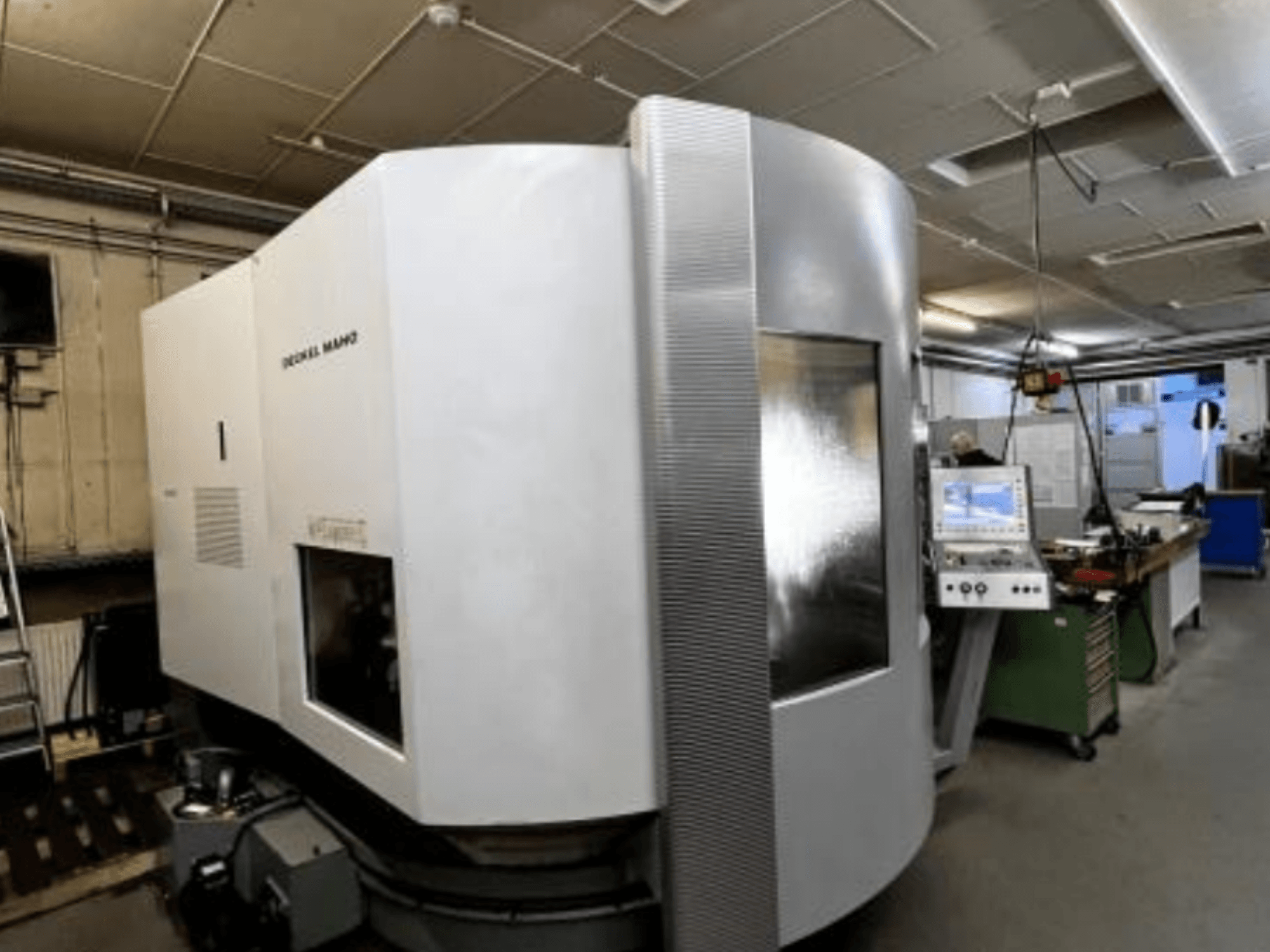 CNC stroj SODICK MAKO v dílně, boční pohled, v pozadí je vidět ovládací panel a pracovní plocha.