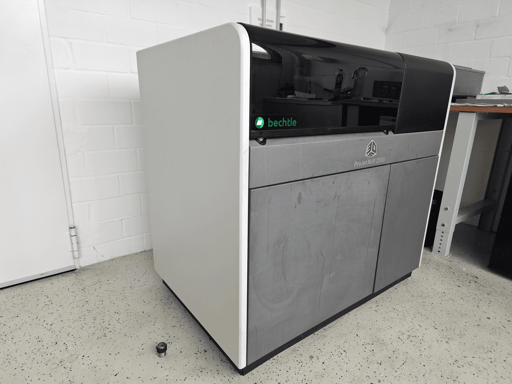 3D tiskárna na plasty 3D Systems ProJet MJP 2500 Plus z čelního pohledu; vyznačuje se elegantním designem s tmavým horním dílem a světlým tělem.