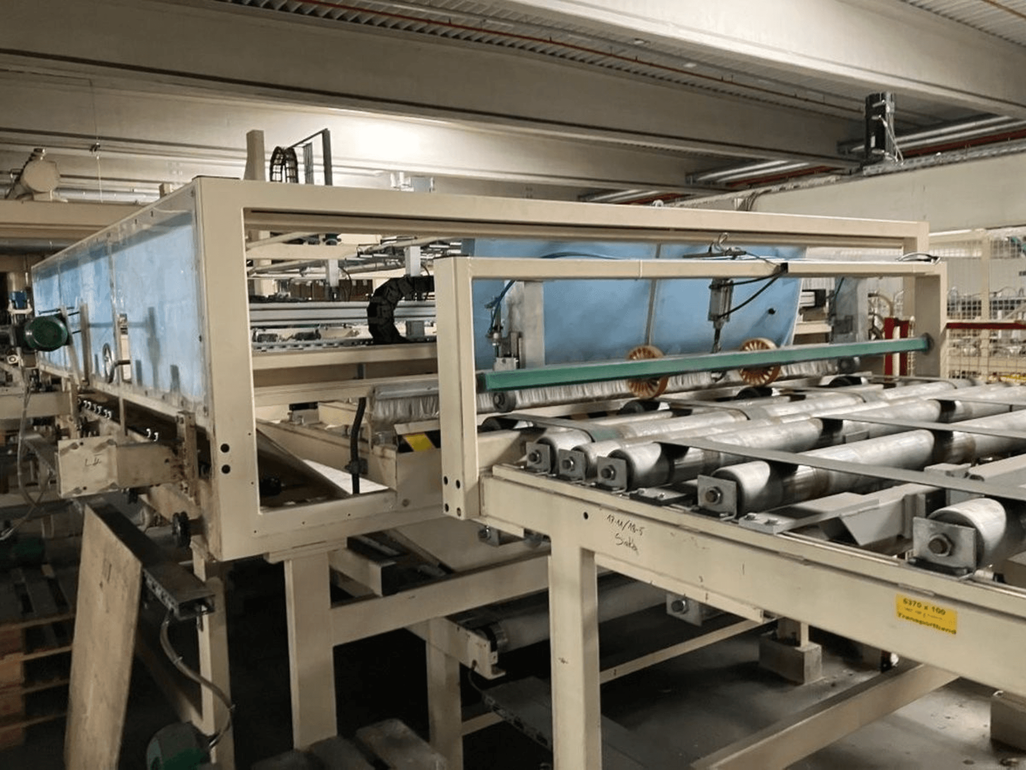 Laminovací lis WEMHÖNER KT-F-1E, pohled z boku, s válci a ovládacími prvky pro zpracování materiálu v továrním prostředí.