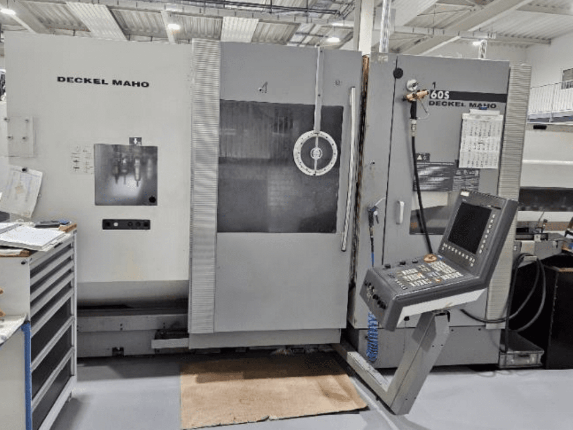 Pohled zepředu na CNC stroj DECKEL MAHO 60S s ovládacím panelem, viditelné nástroje, v dílně.