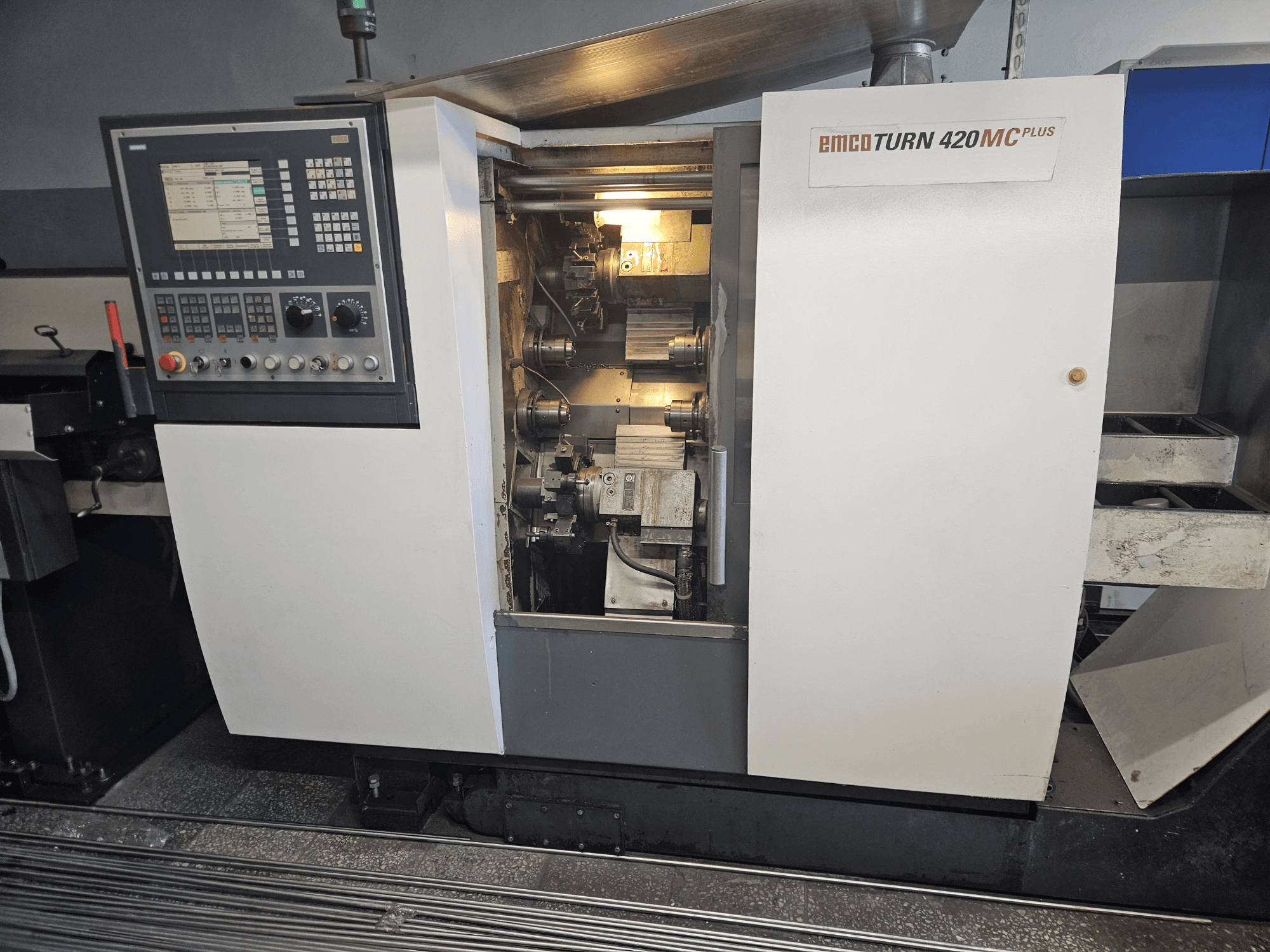 Vícevřetenový stroj EMCO TURN 420 MC Plus, pohled zepředu na ovládací panel a vnitřní komponenty.