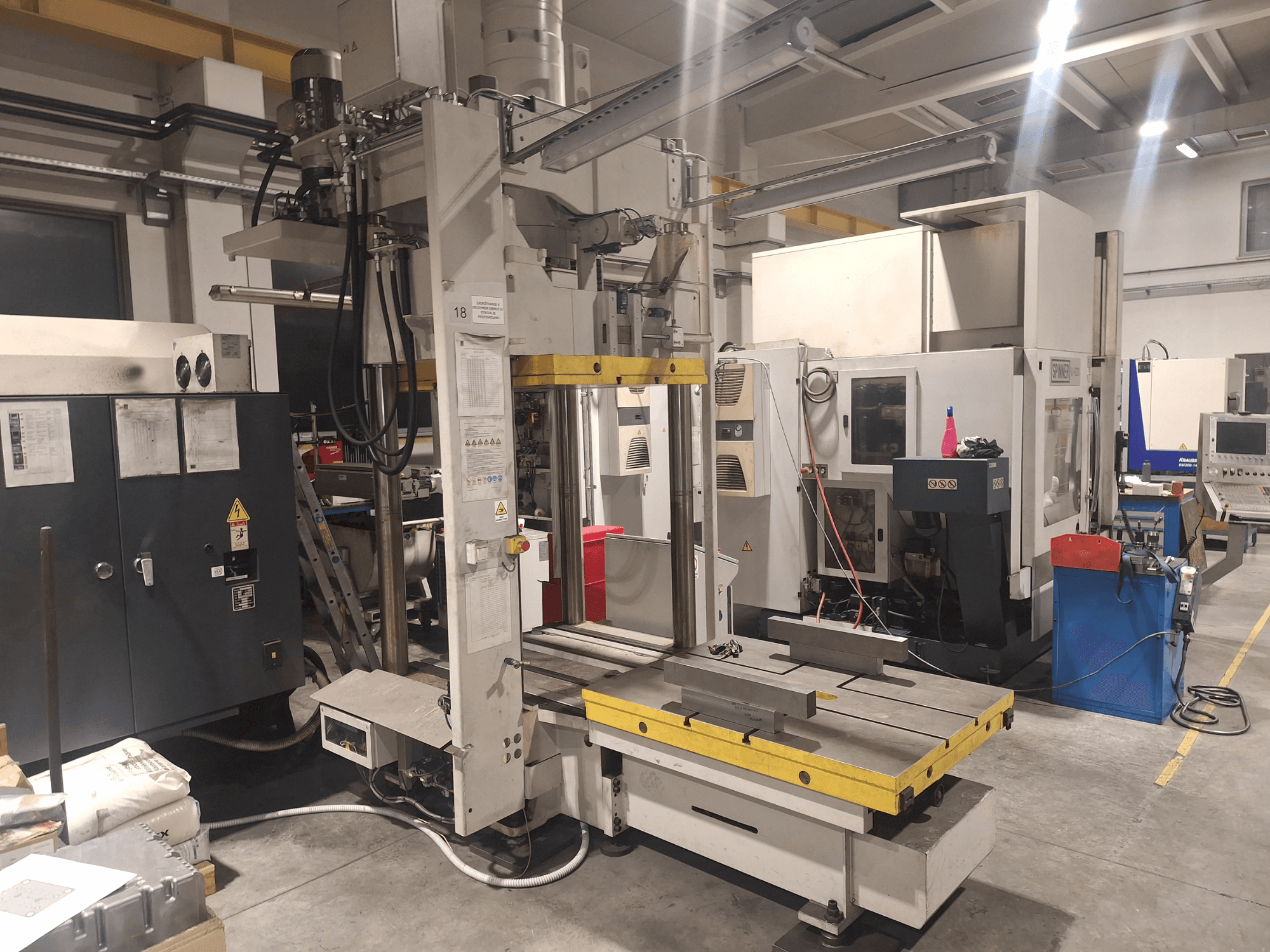 Horizontální frézka od společnosti Synergic, pohled zepředu; široký stůl a různé ovládací panely v dílenském prostředí.