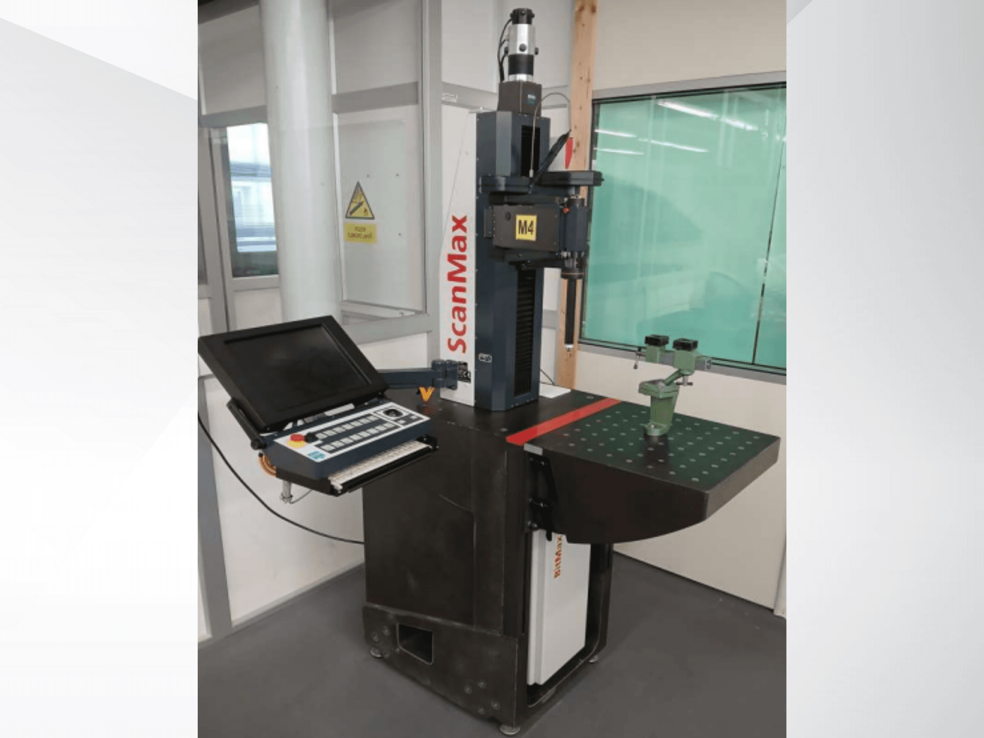 Měřicí stroj ScanMax M4, čelní pohled s ovládacím panelem a zeleným kalibračním přípravkem na tečkovaném pracovním stole.