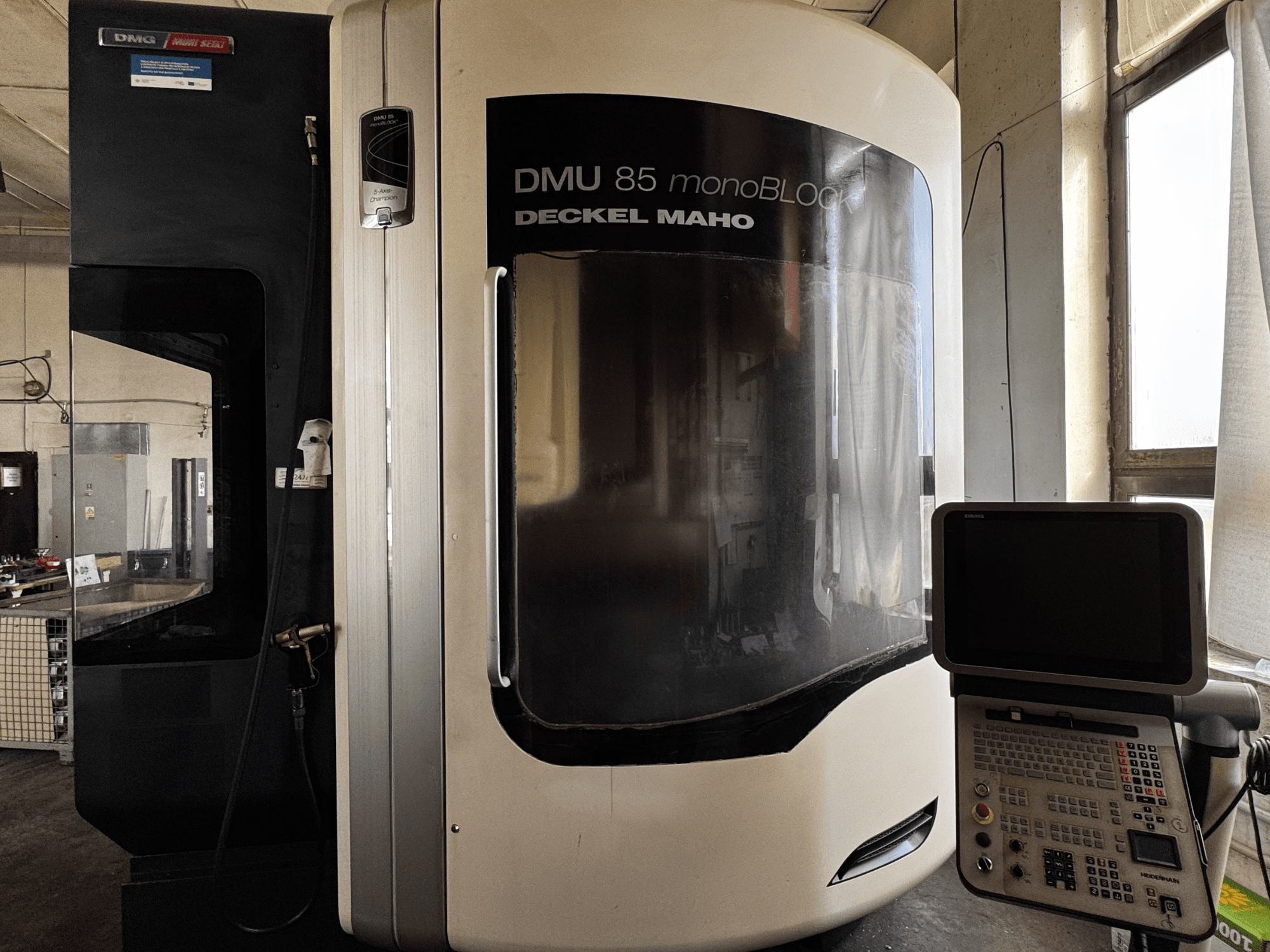 Vertikální obráběcí centrum DMG MORI DMU 85 monoBLOCK, pohled zepředu s ovládacím panelem a velkým průzorem.