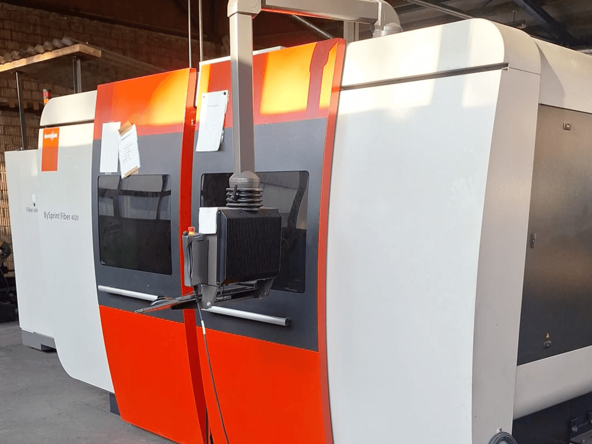 Laserový řezací stroj BySprint Fiber 4020, boční pohled, červenobílý exteriér, viditelný detailní ovládací panel.