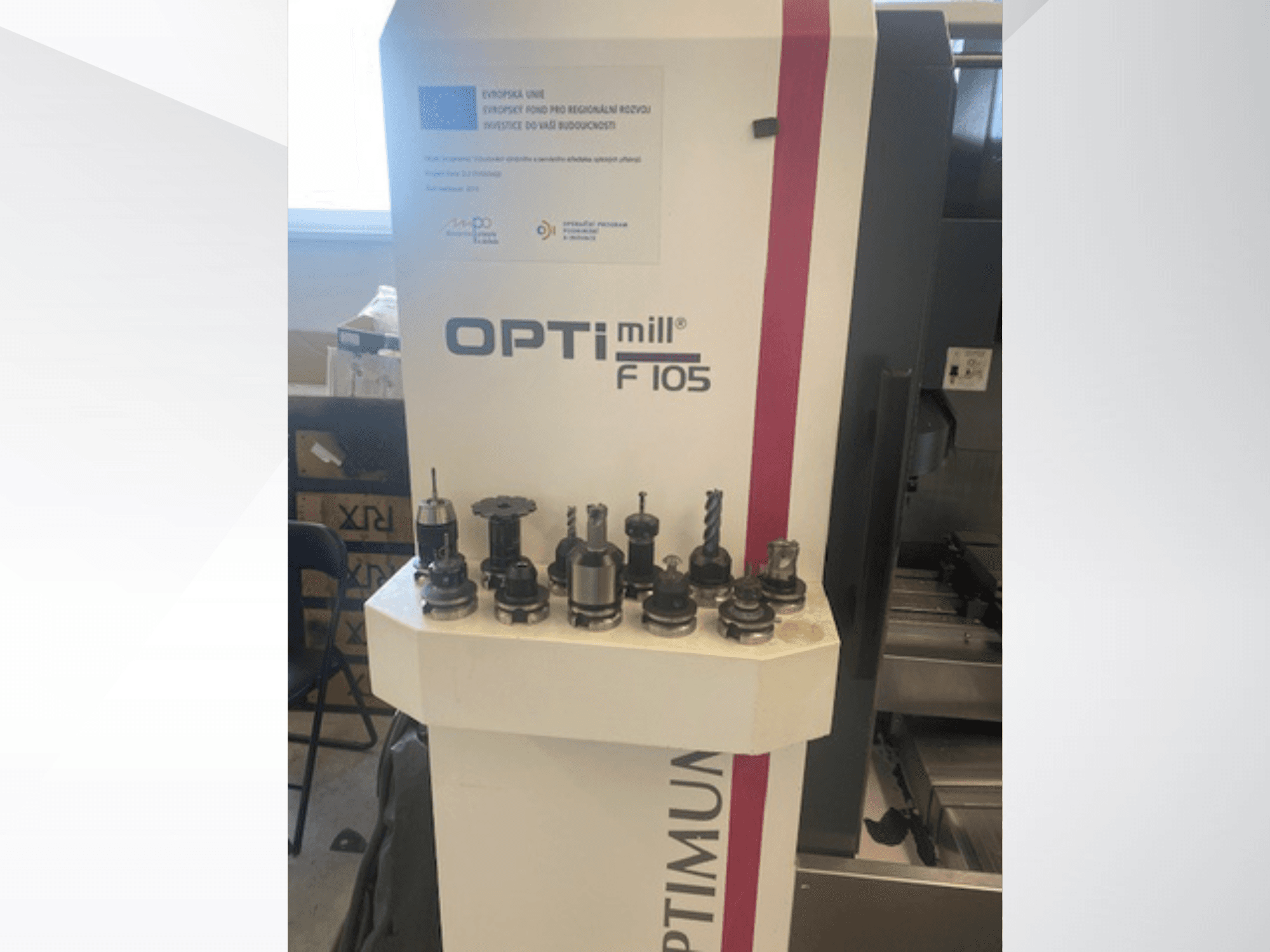 Pohled zepředu na vertikální obráběcí centrum Optimum Optimill F105 s různými připojenými nástroji zobrazenými po boku.